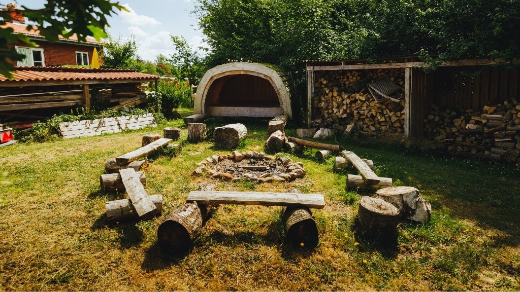 Feuerstelle mit Holzbänken und Unterstand auf dem Solbakken Naturistcamping.