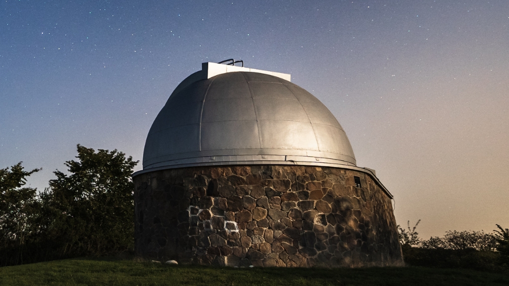 Observatoriets kuppel oplyst under en stjerneklar nattehimmel.