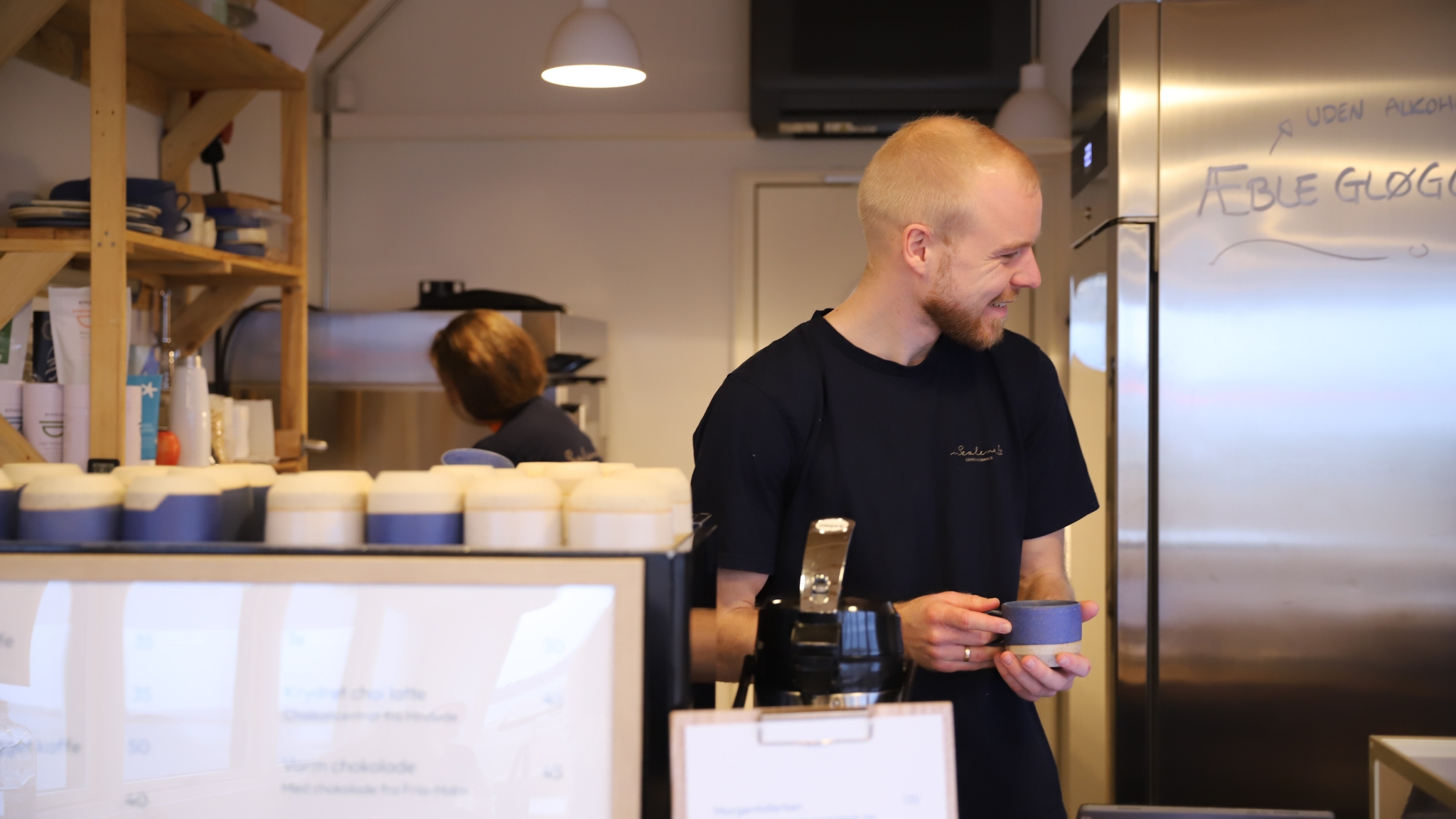 Barista hinter der Theke im Sealevel Kaffebar mit einer Tasse in der Hand.