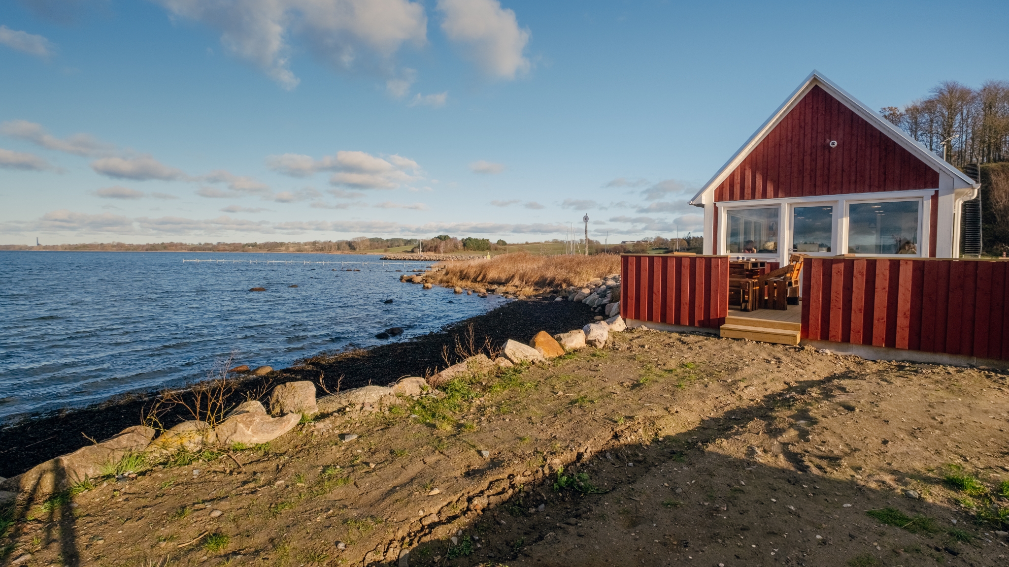 Sealevel Kaffebar i rød bygning ved kysten med udsigt over vandet.