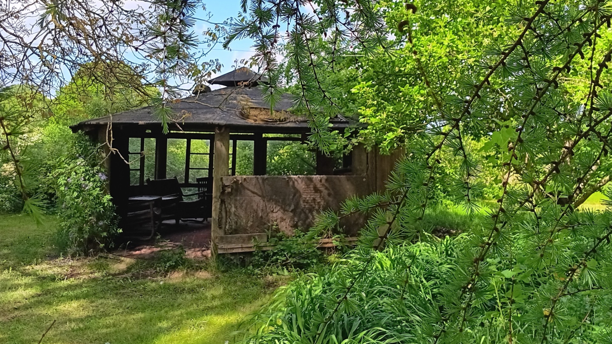 Covered seating area with table and benches at the shelter site at Niks Malergård.