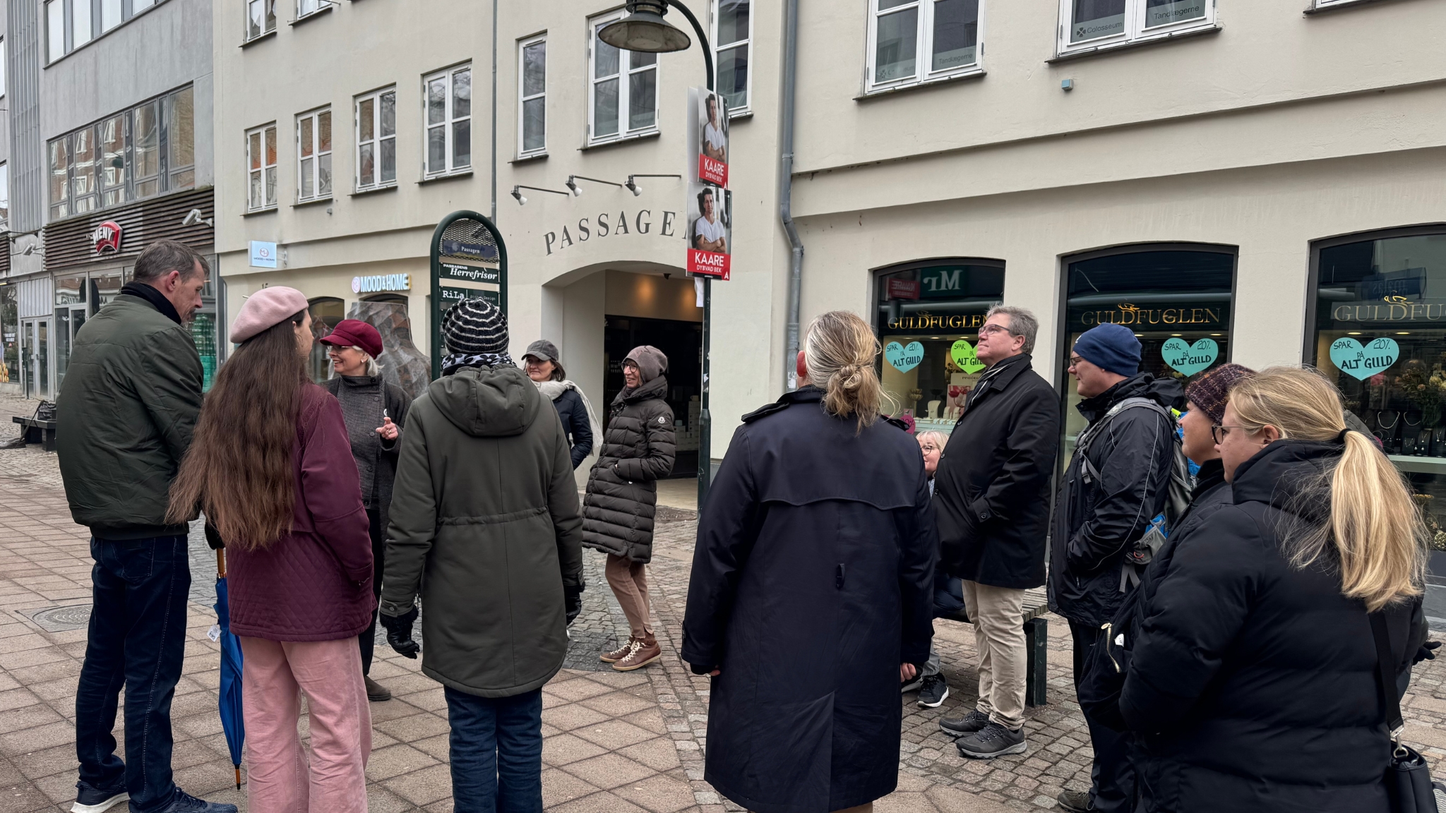 Guided tour in central Roskilde with group standing in a pedestrian shopping street.