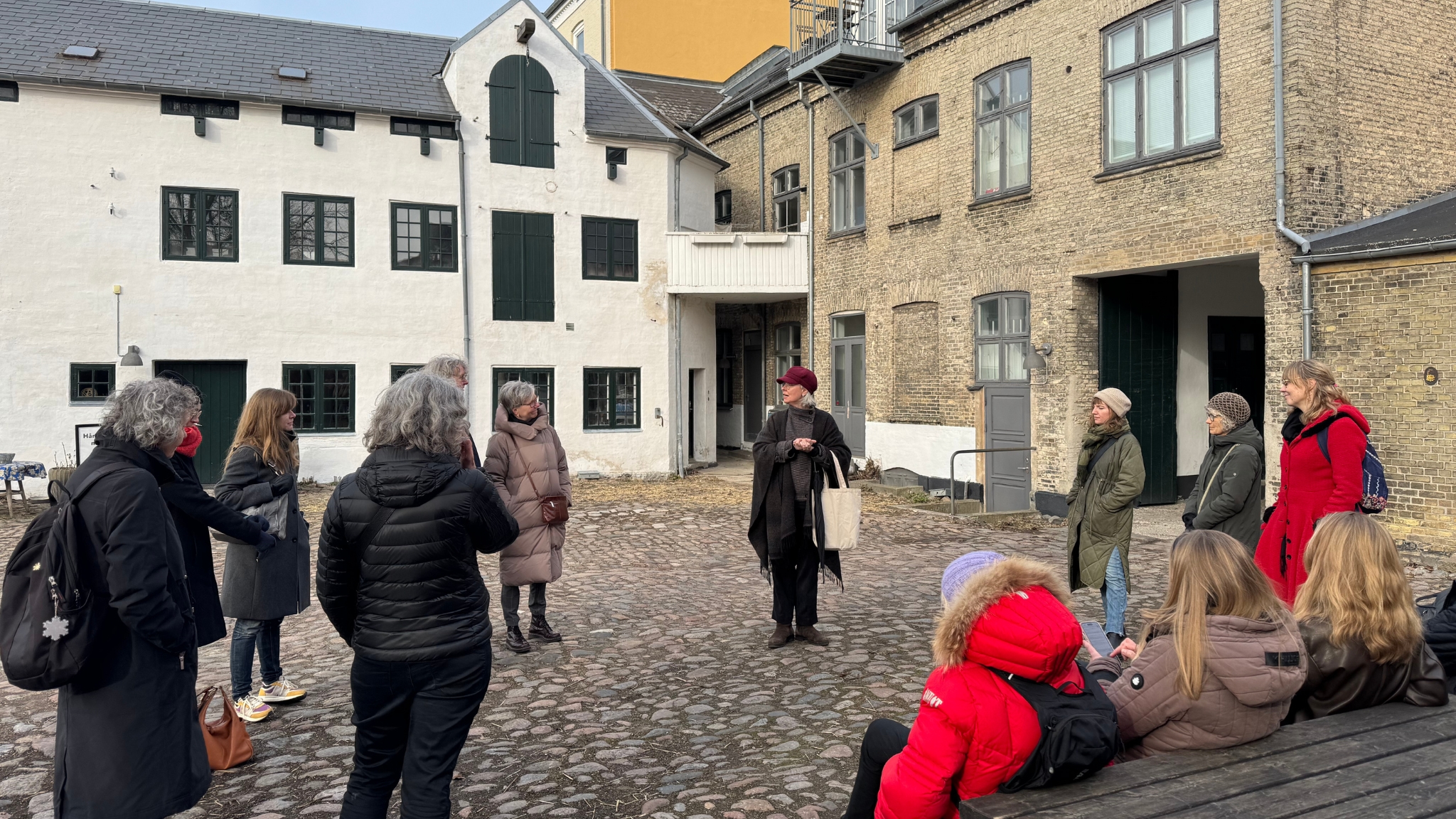 Guided city walk in Roskilde in a historic courtyard with guide and participants.
