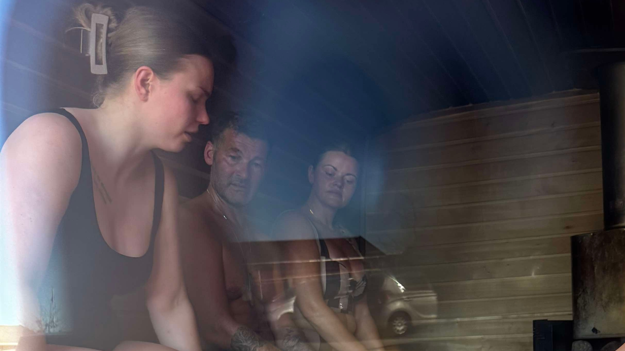 Three people relaxing in a sauna with natural light in Frederikssund.