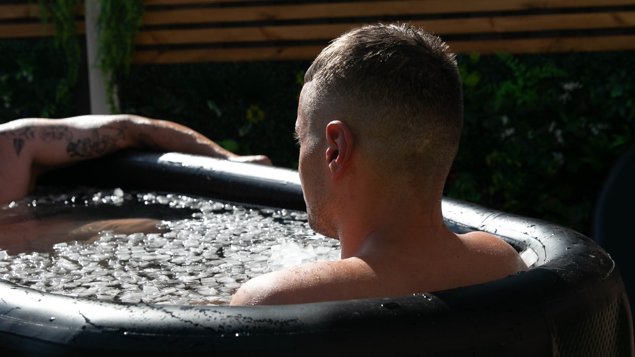 Person sitting in an outdoor ice bath filled with ice cubes in Frederikssund.