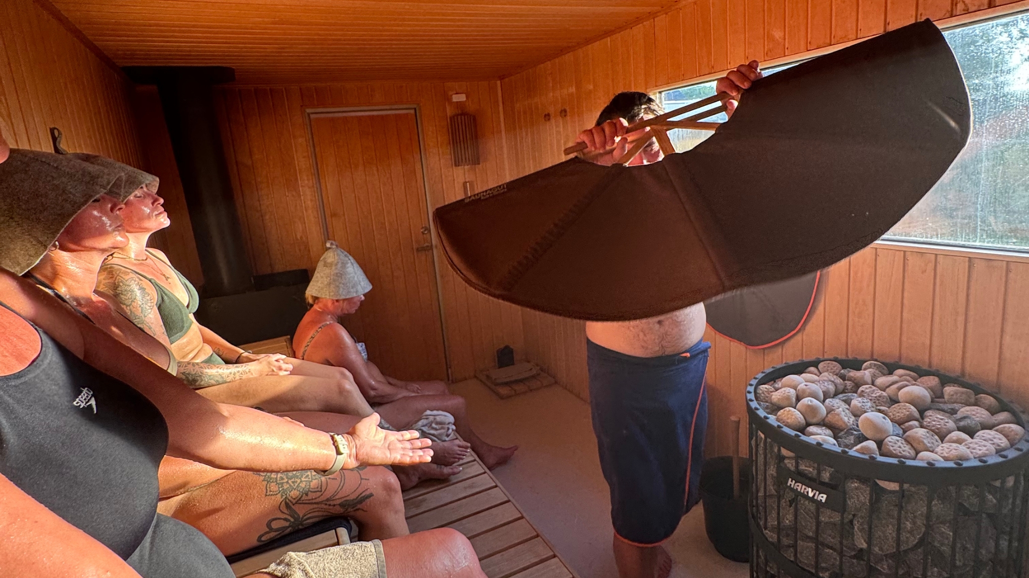 Sauna master waving a towel over hot stones during a sauna session in Frederikssund.