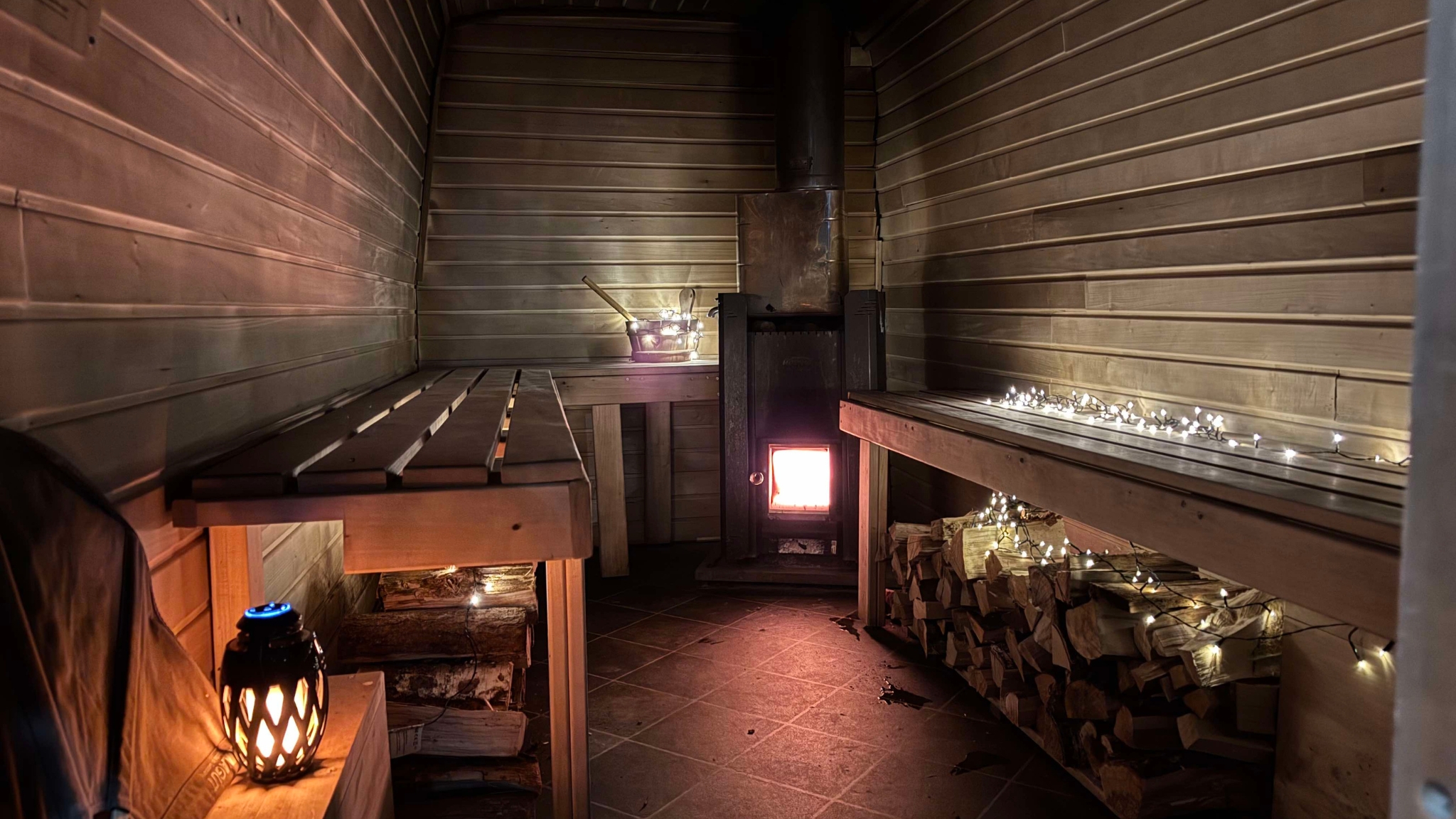 Sauna with wood-burning stove and cozy lighting in Frederikssund.