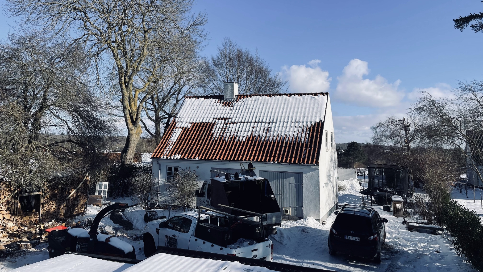 Guest house in Kattinge with snow-covered roof and garden viewed from outside in winter.