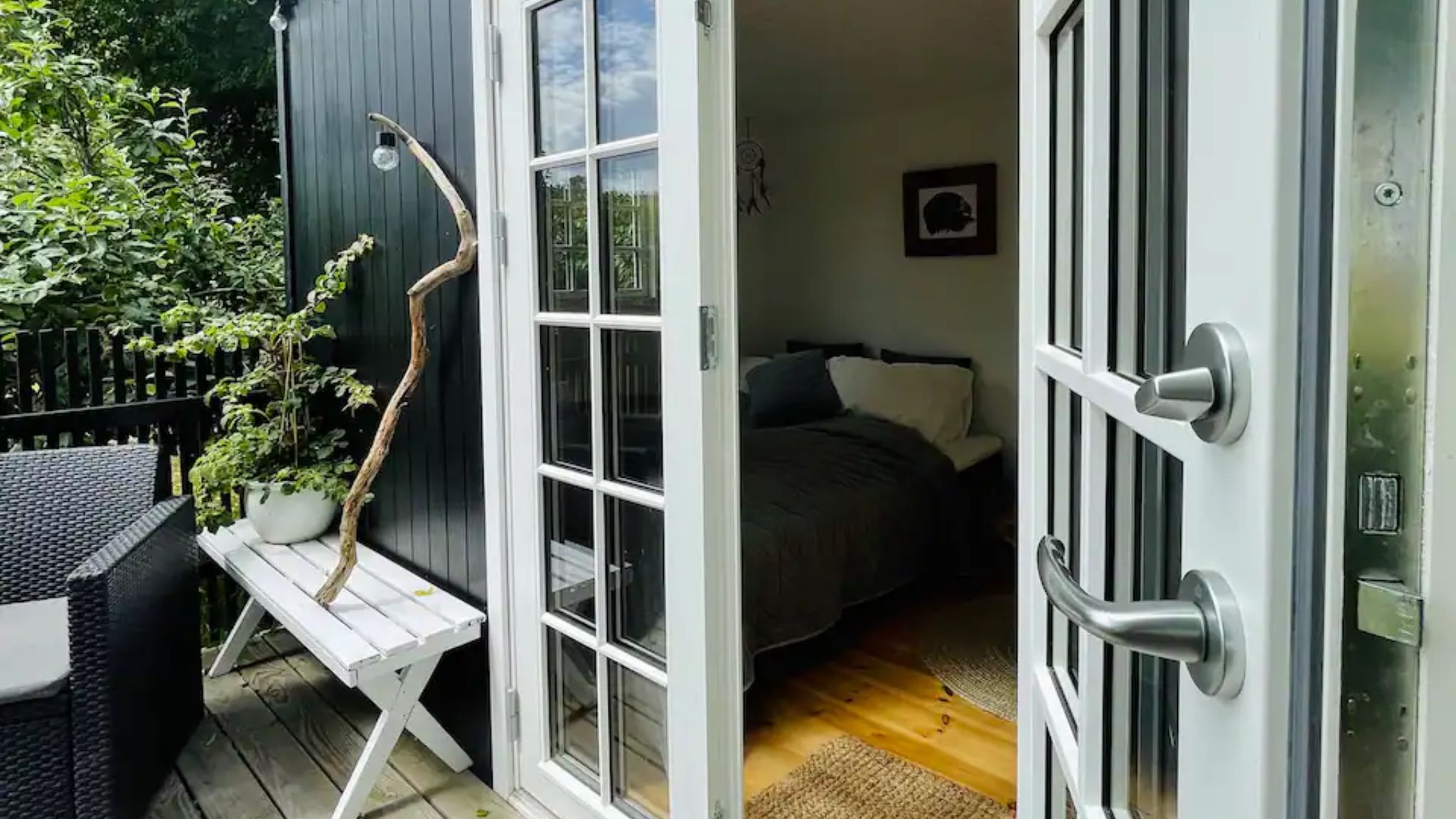 Terrace and open doors to a Tiny House in Gl. Lejre with a view into the interior.