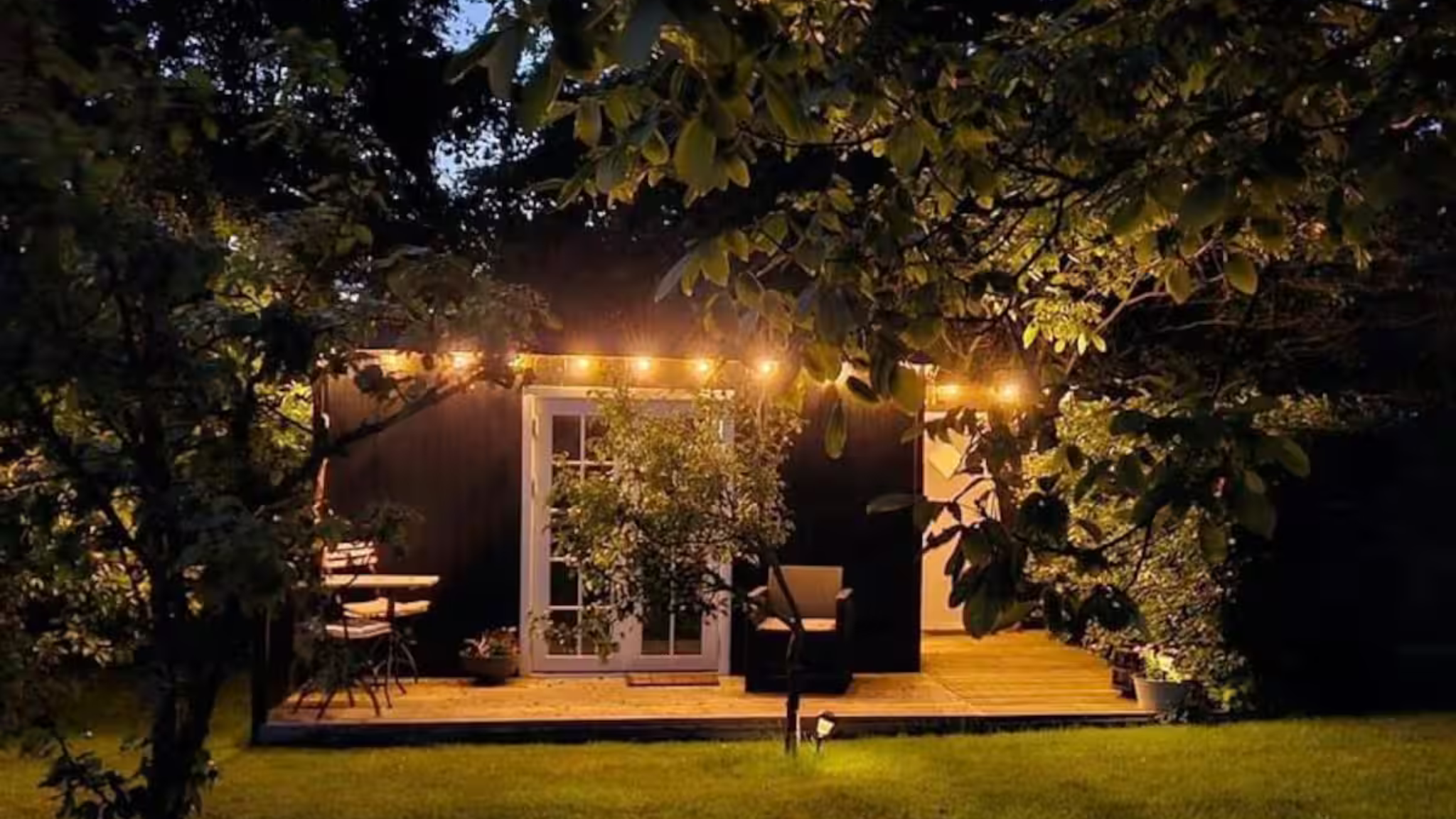 Tiny house with string lights in the garden at evening.