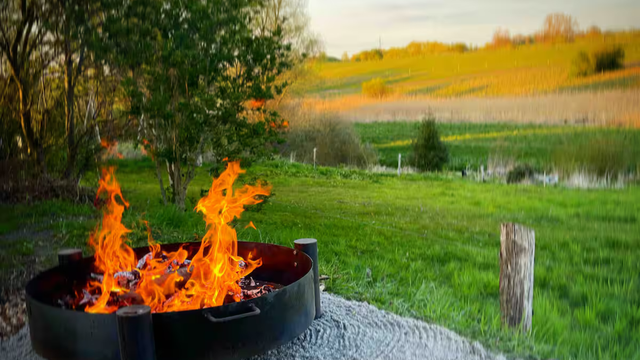 Fire pit with flames and views over nature at Tiny House Gl. Lejre.