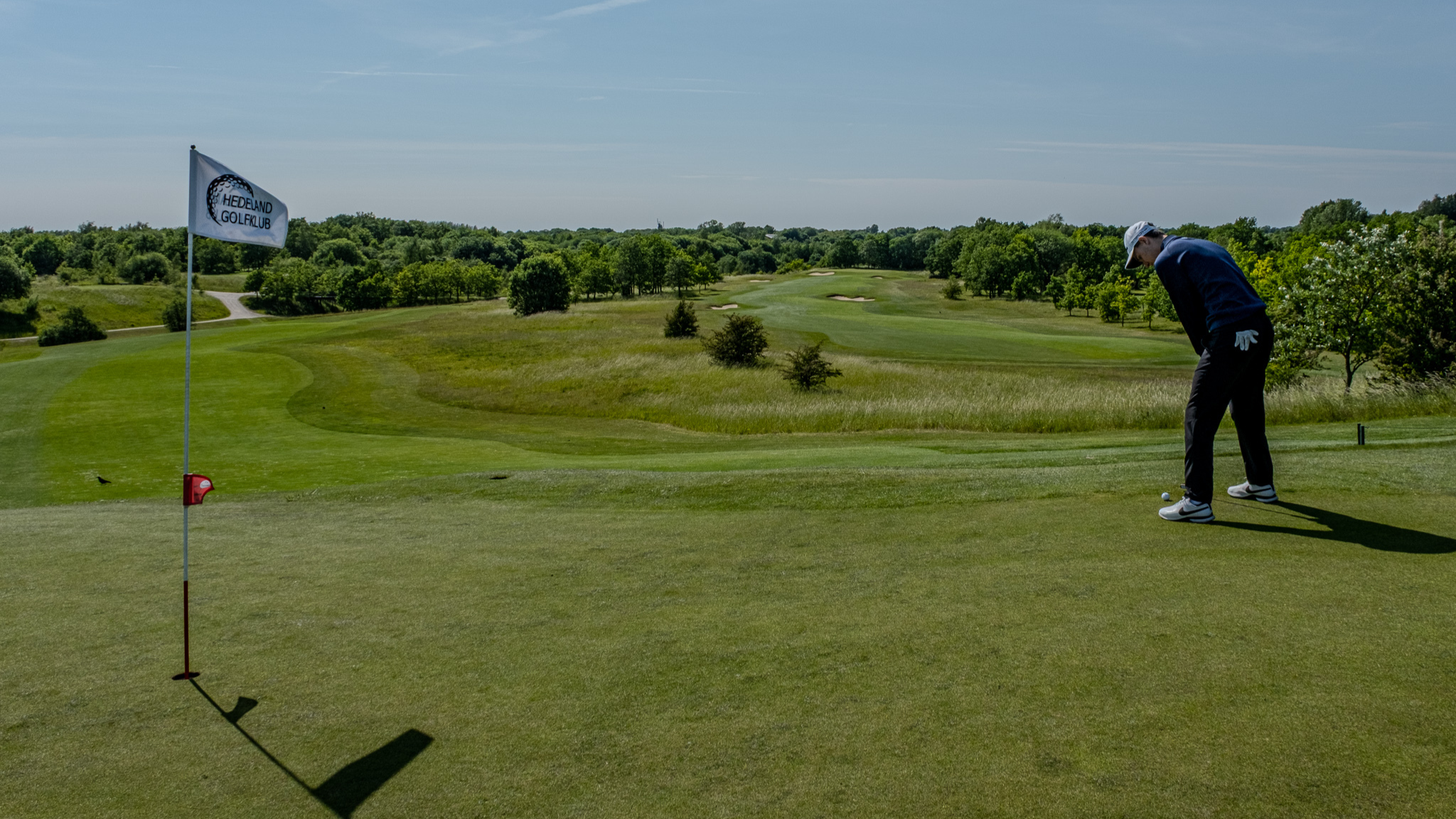 Golfer on the green at Hedeland Golf Club surrounded by green landscape.