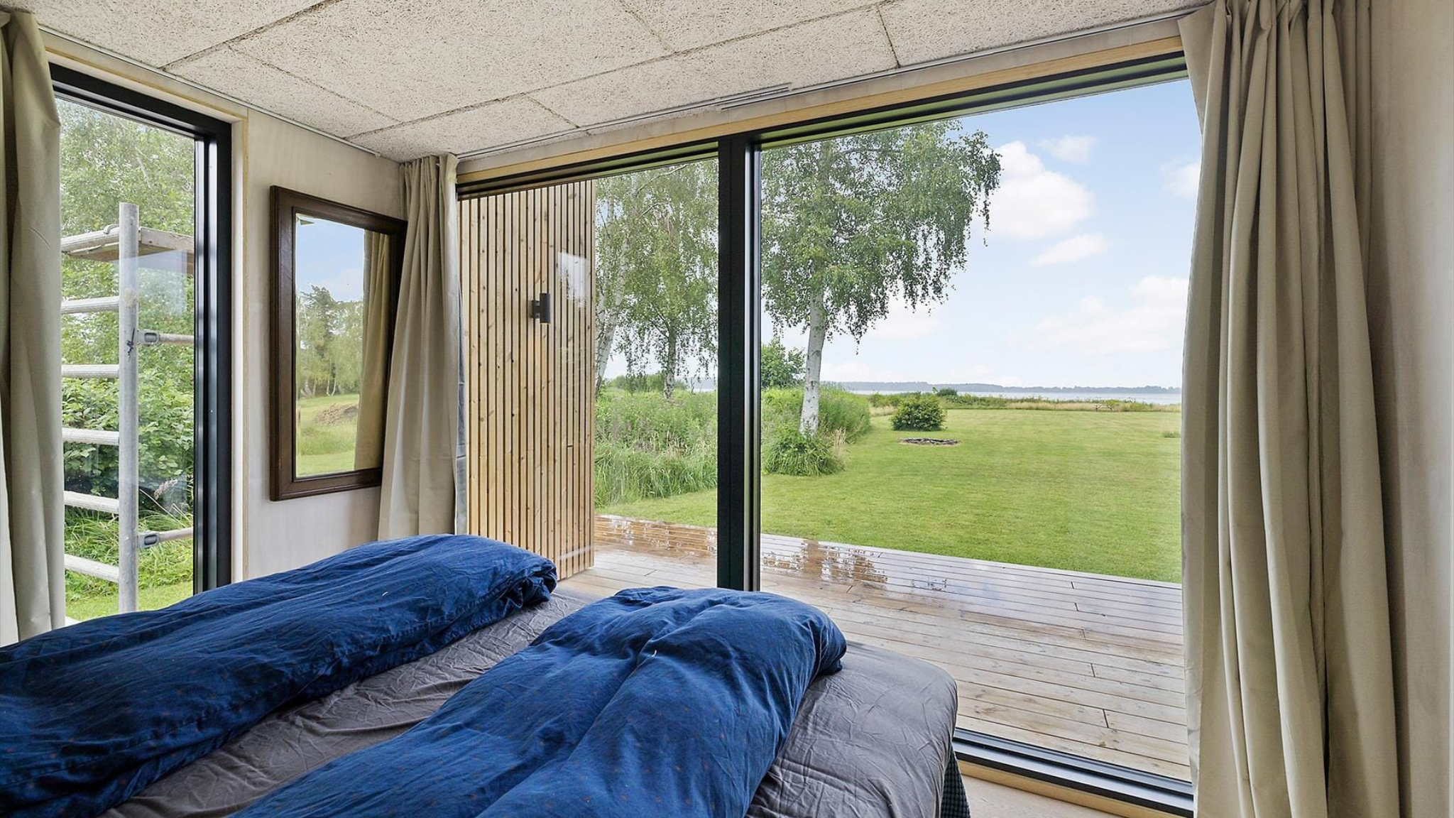 Soveværelse med store vinduer og udsigt over fjorden.