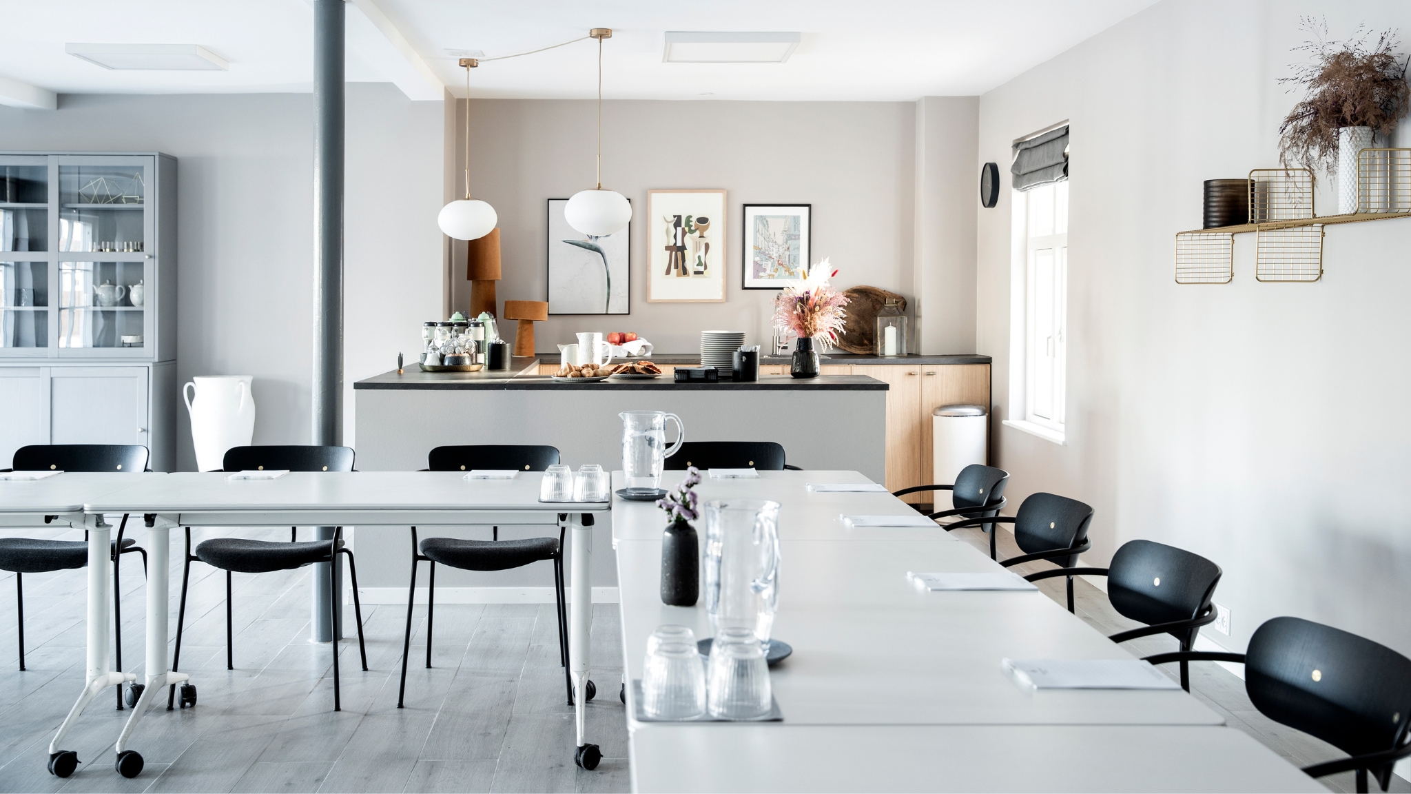 Modern meeting room at Skjalm Hvide Hotel with table setup and open kitchen area.