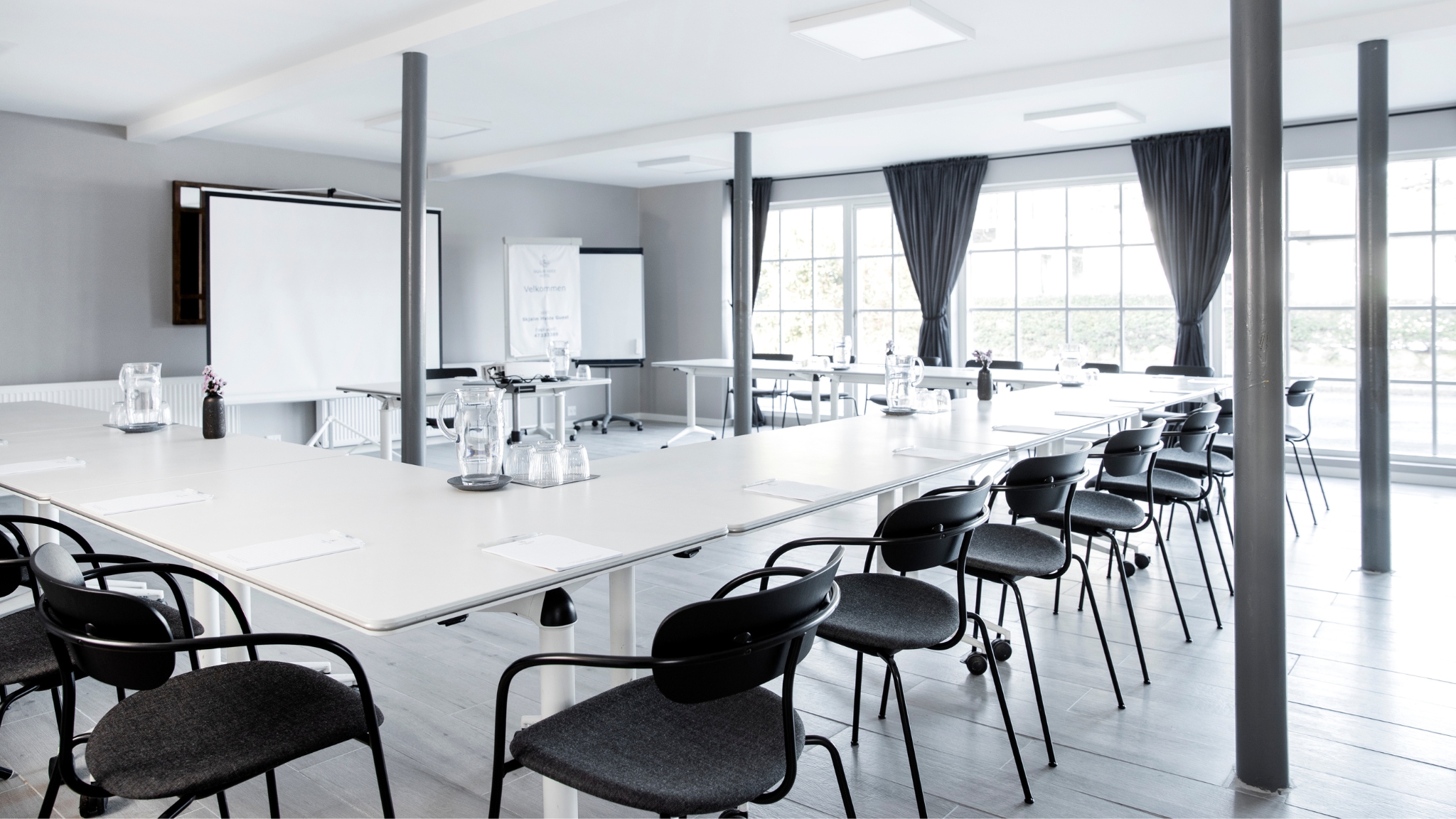 Conference room at Skjalm Hvide Hotel with projector screen and U-shaped table setup.