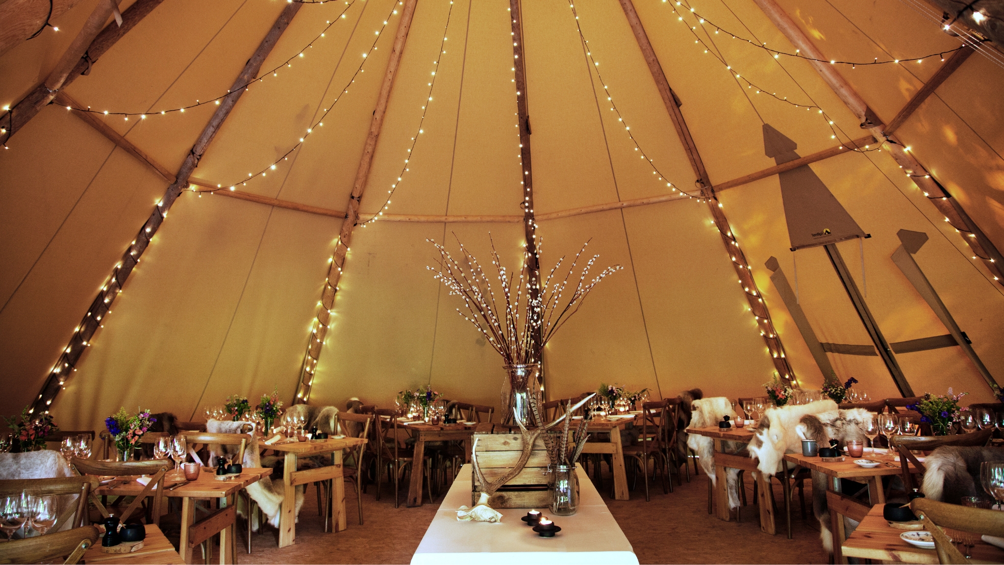 Atmospheric event tent at Herthadalen with fairy lights and rustic table settings.