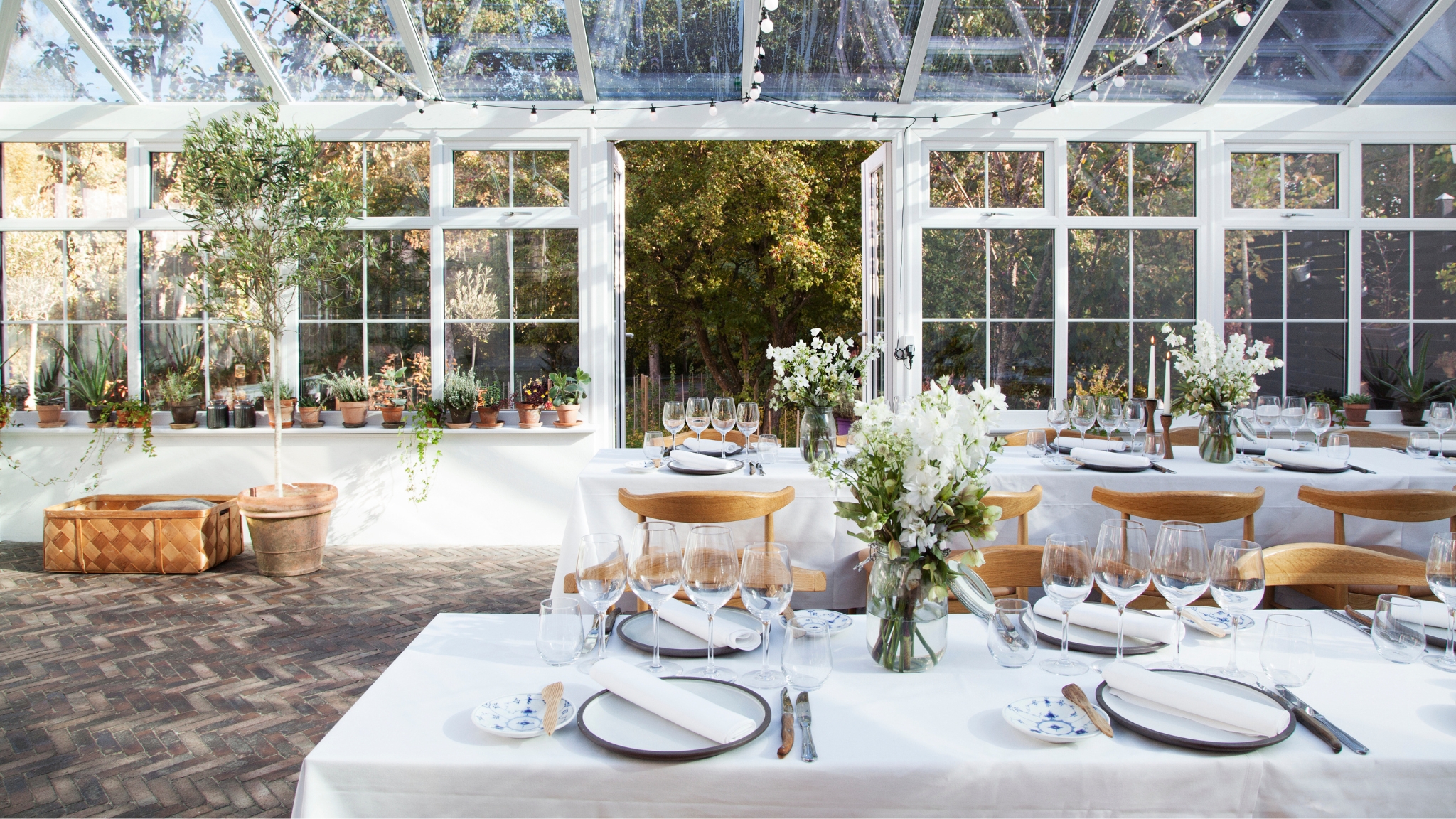 Heller Wintergarten in Herthadalen mit eleganter Tischdekoration und Blick in den Garten.