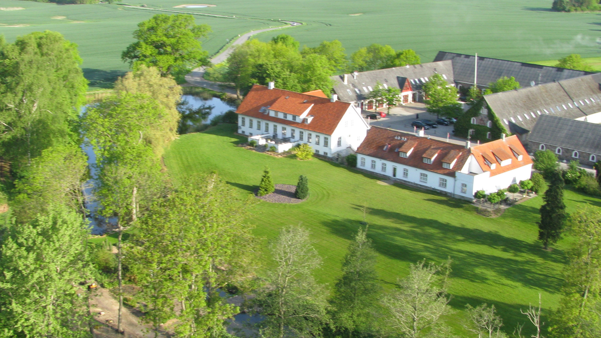 Luftfoto af Sonnerupgaard Gods omgivet af grønne marker og søer.