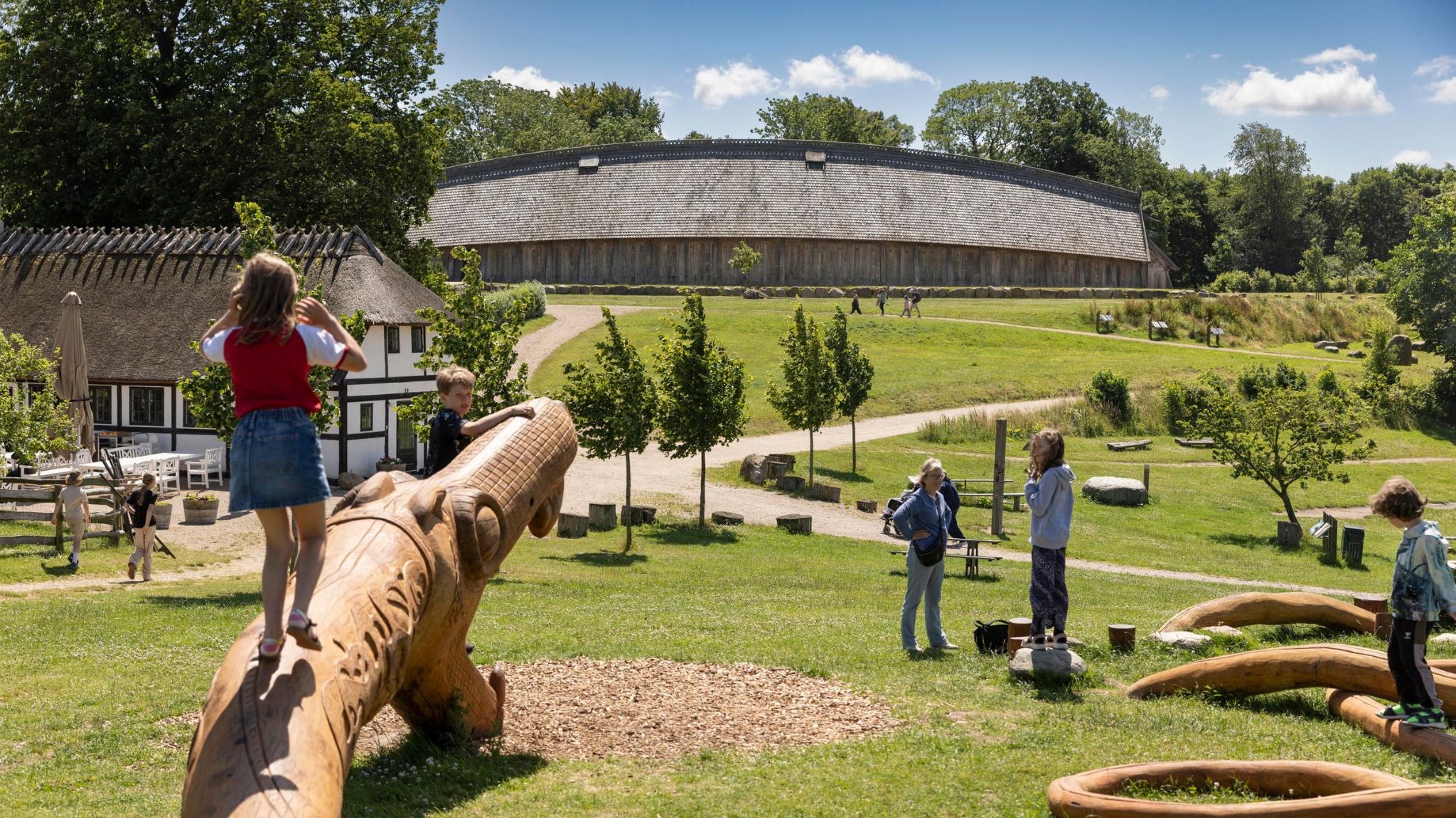 Children playing in the activity area with the King's Hall in the background at Sagnlandet Lejre.