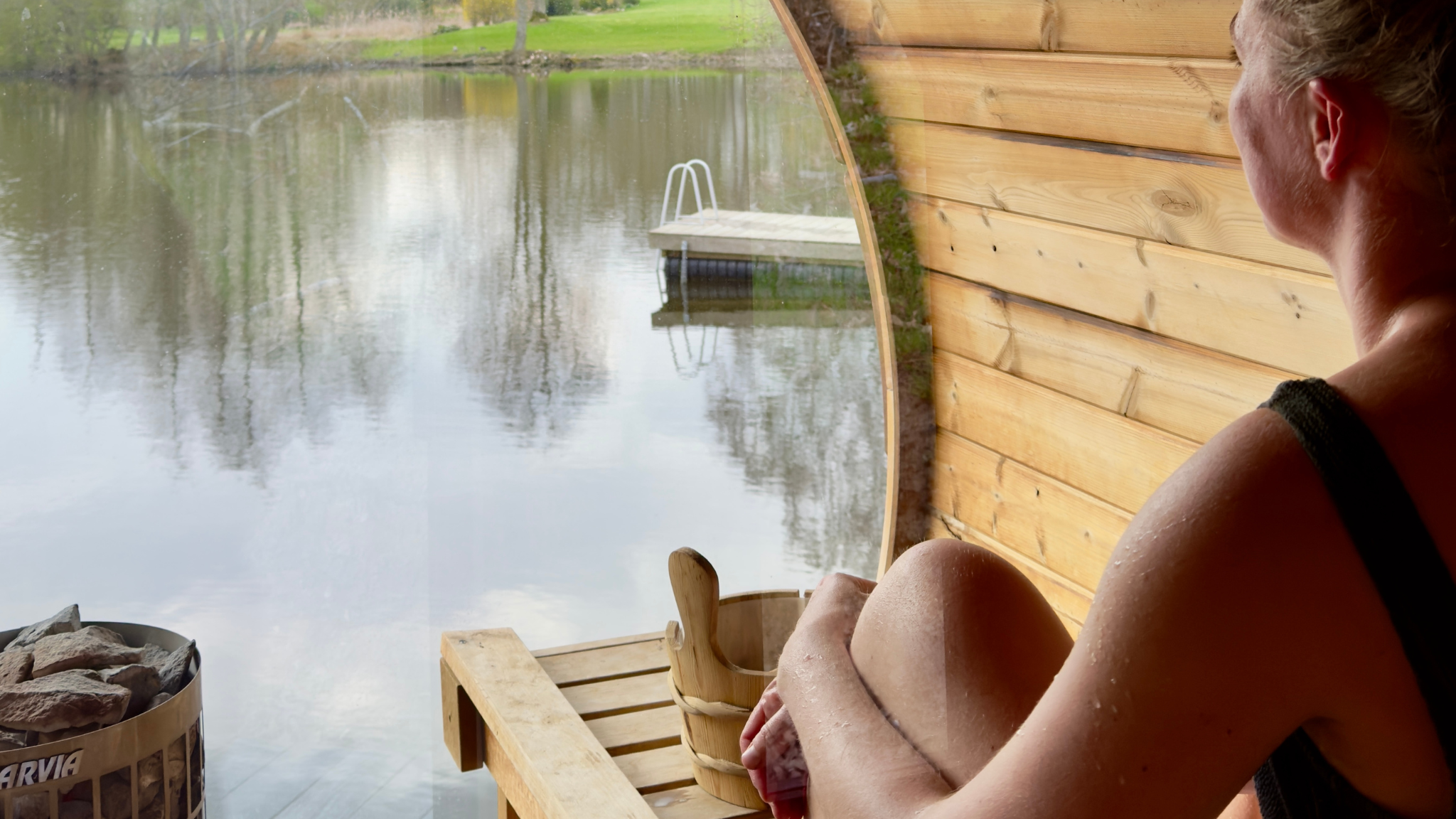 Person relaxing in a sauna at Sonnerupgaard Gods overlooking the lake and bathing jetty.