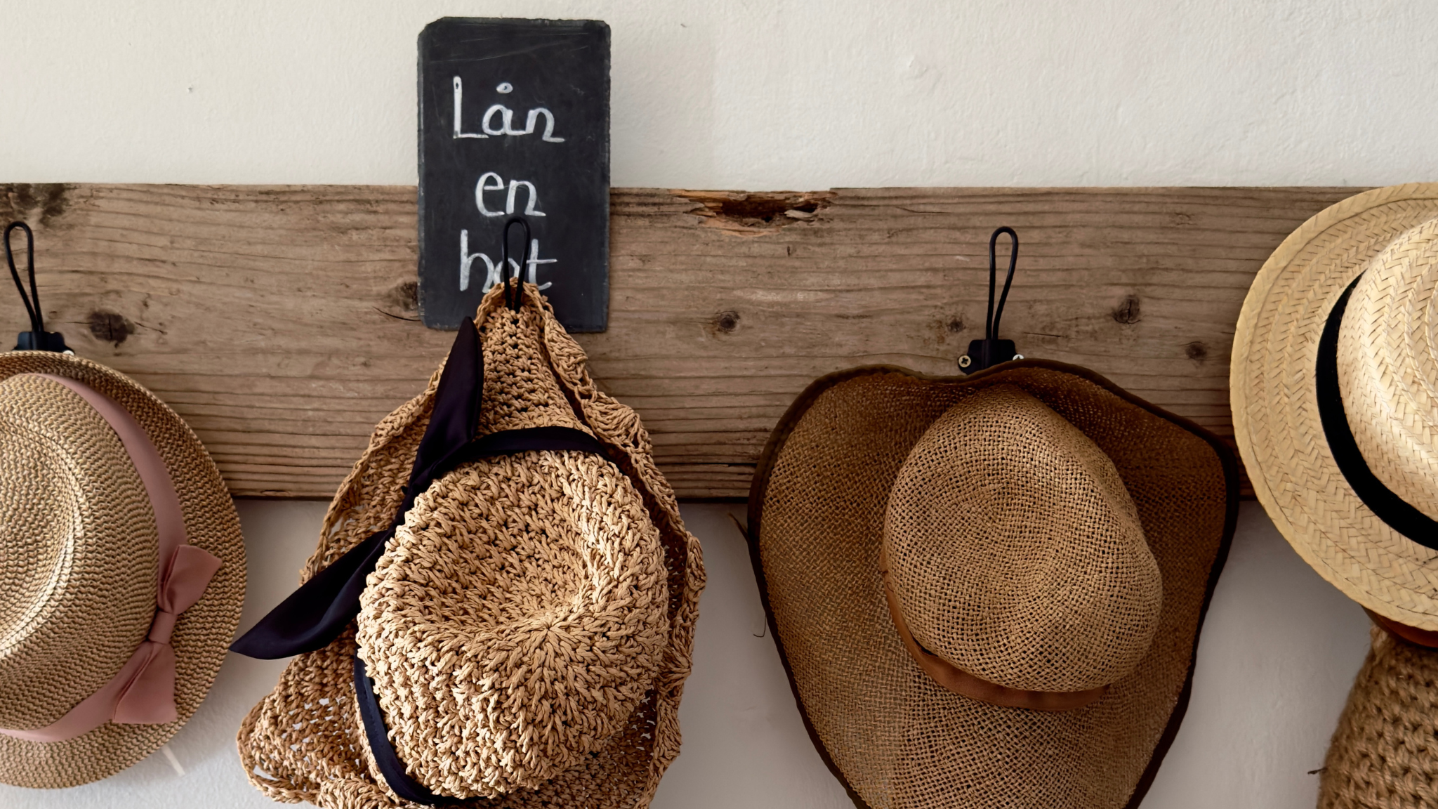 Geflochtene Hüte und Tasche an einer rustikalen Garderobe im Gershøj Kro og Strandhotel.