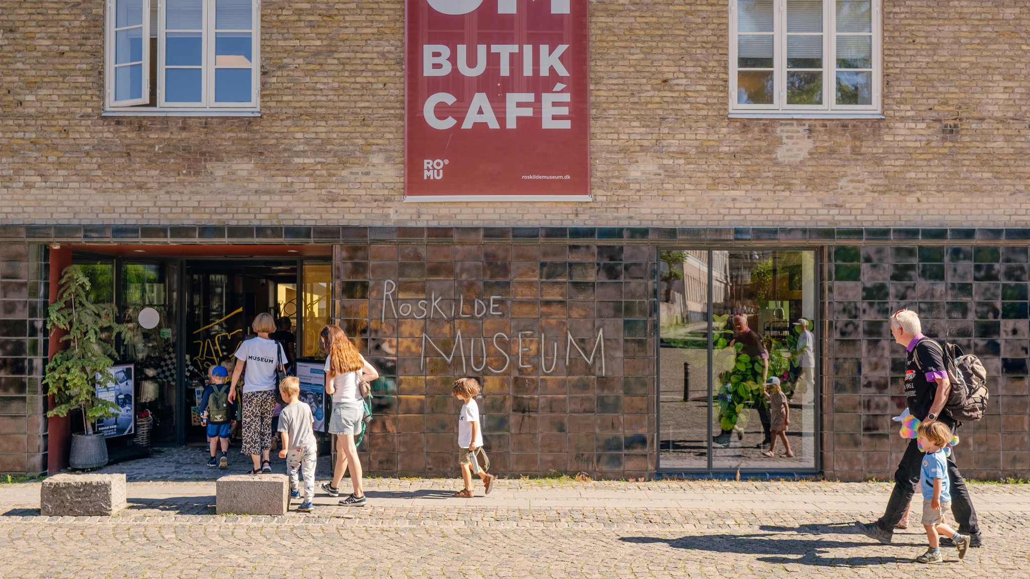 Visitors at the entrance to Roskilde Museum with museum shop and café in the historic museum building.