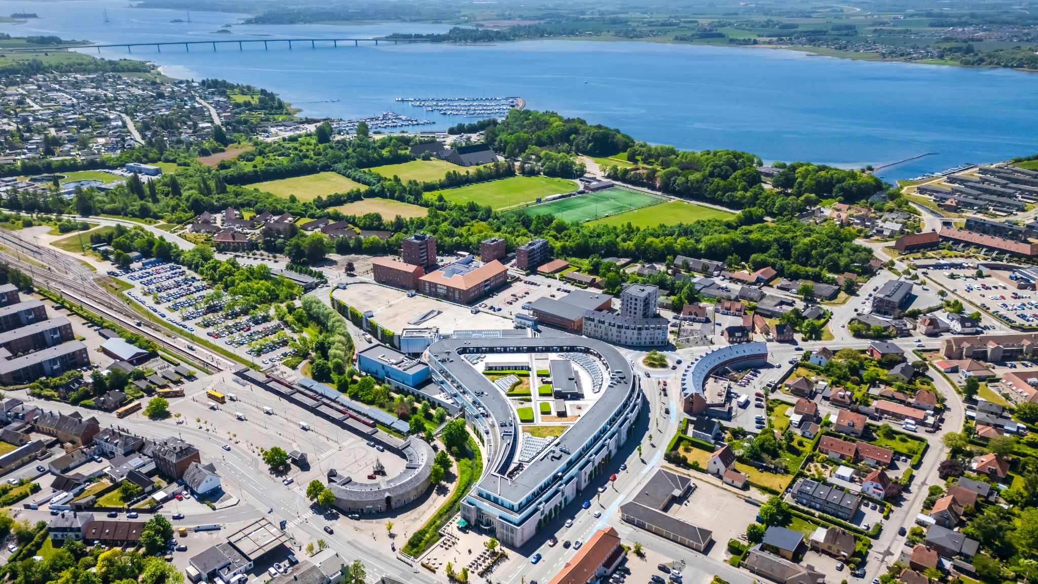 Luftaufnahme von Sillebroen Shopping in Frederikssund mit der Stadt und dem Roskilde Fjord im Hintergrund.