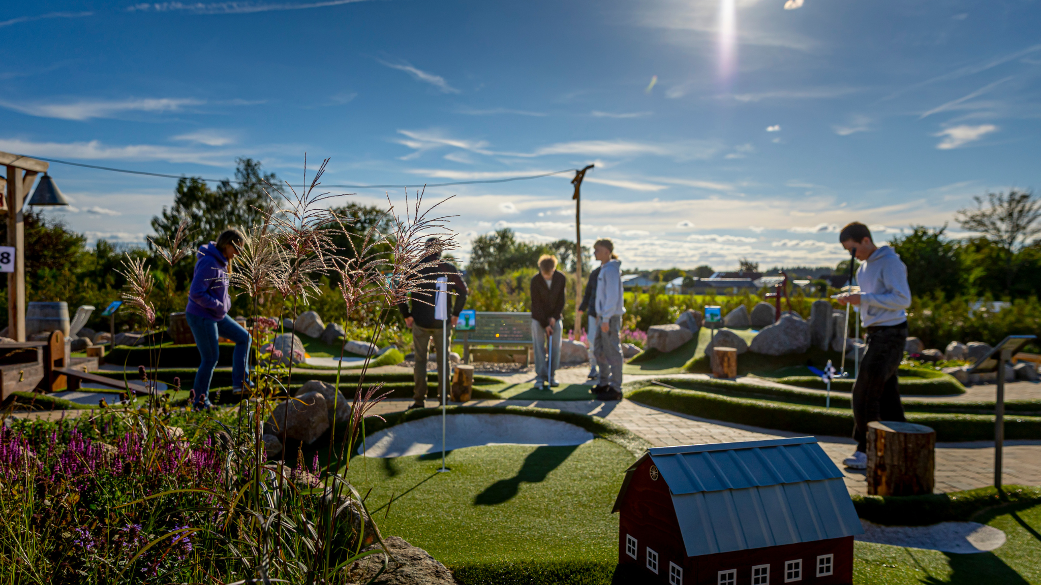 Gäste spielen Minigolf bei Countryside Adventure in grüner und ländlicher Umgebung.