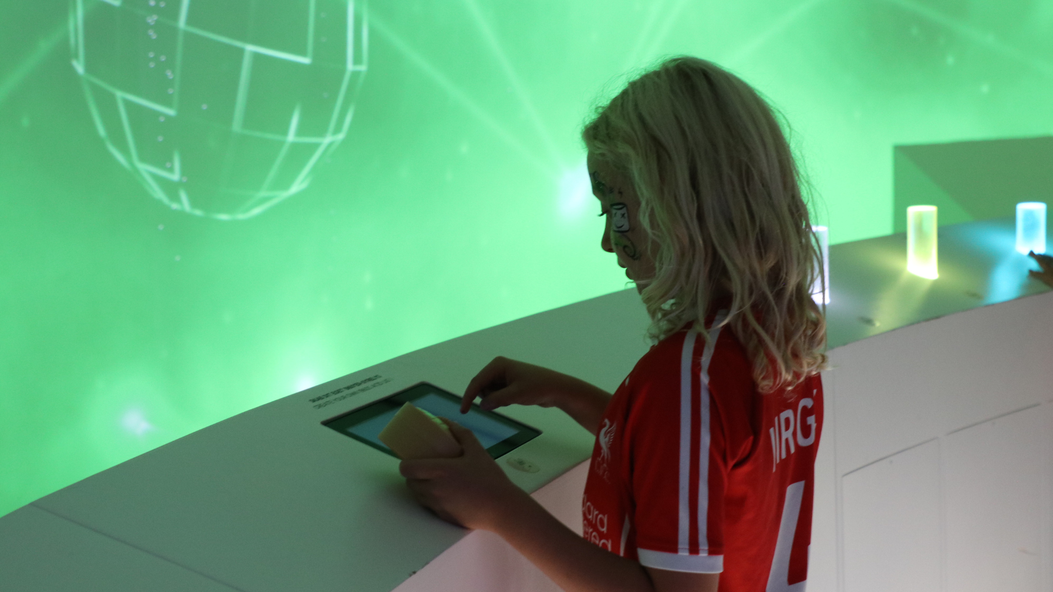 Child exploring an interactive installation with green lighting at the rock museum.