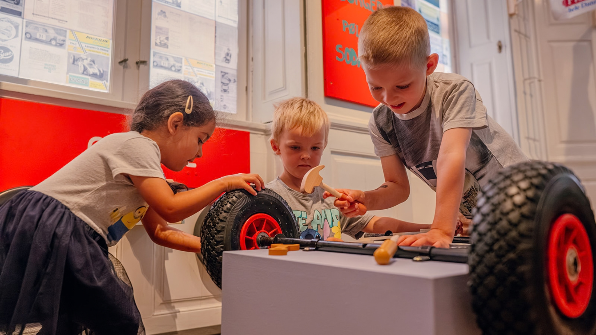 Three children explore a car using tools at Roskilde Museum.
