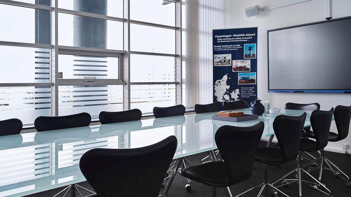 Meeting room at Roskilde Lufthavn with a glass table, black chairs and large windows