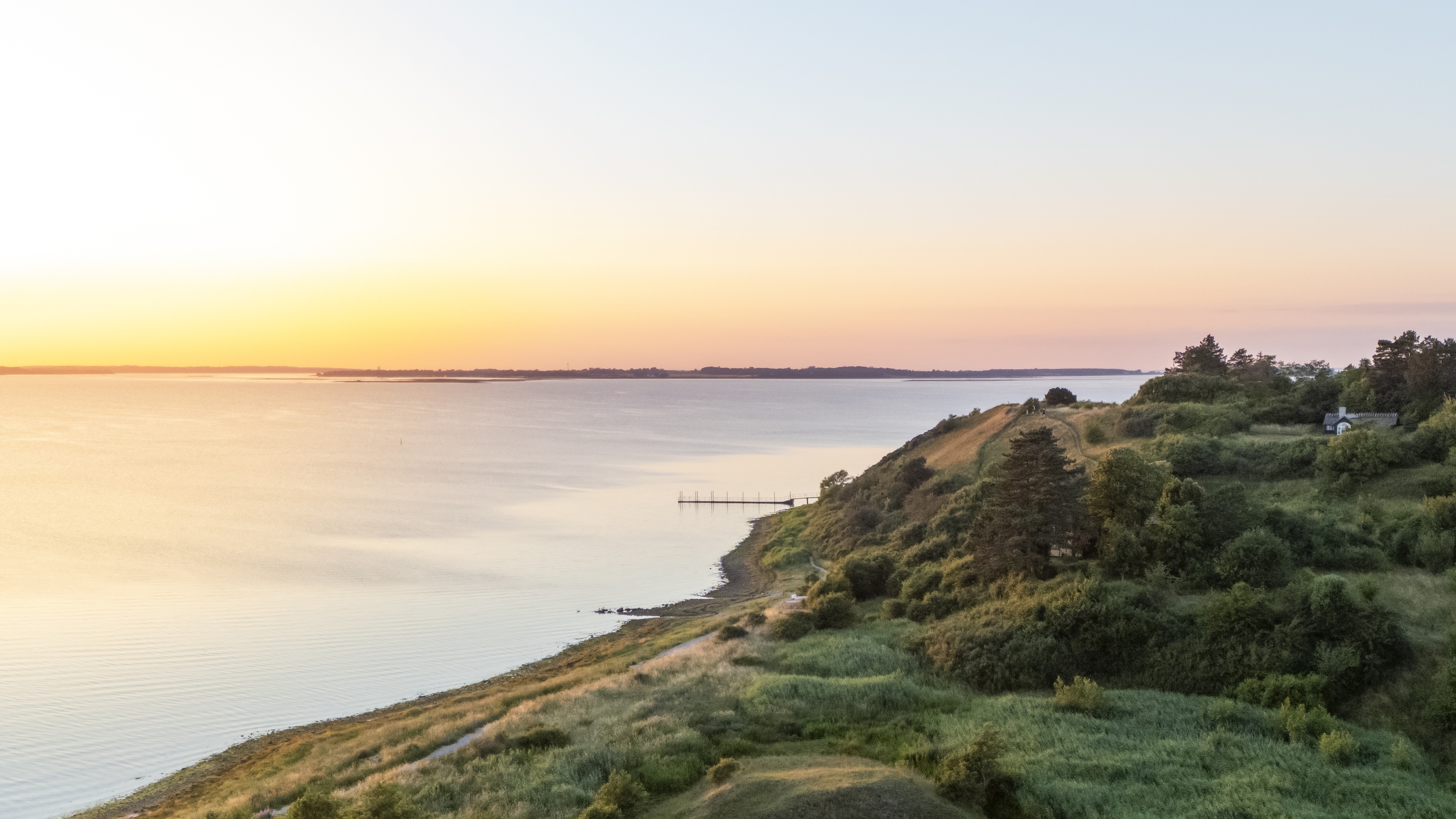 Green coastal slopes at Ejby Ådal overlooking Isefjord in golden evening light.
