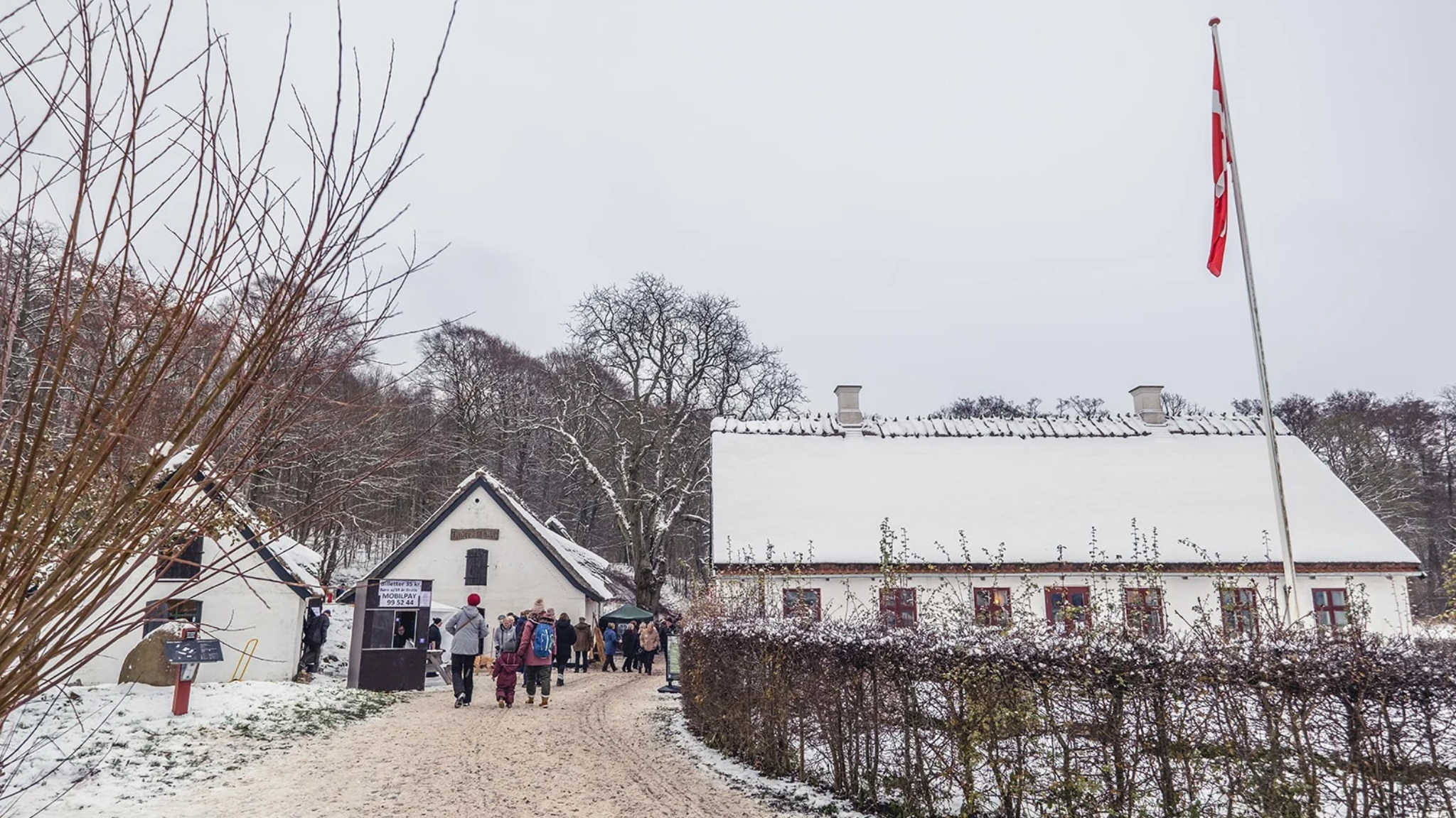 Weihnachtsmarkt an der Tadre Mølle bei Hvalsø mit Besuchern, schneebedeckten Gebäuden und winterlicher Atmosphäre.