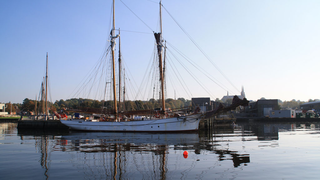 Holzboot im Hafen Roskilde mit dem Dom im Hintergrund