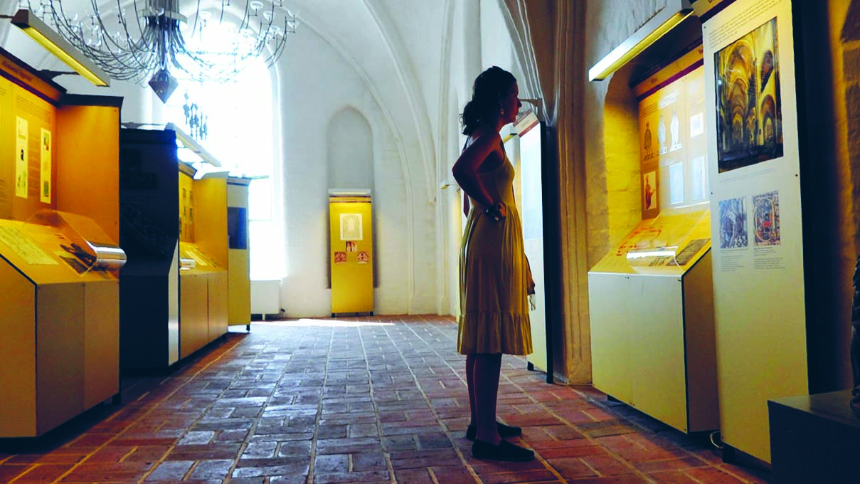Visitor viewing exhibits beneath the vaults of Roskilde Cathedral Museum
