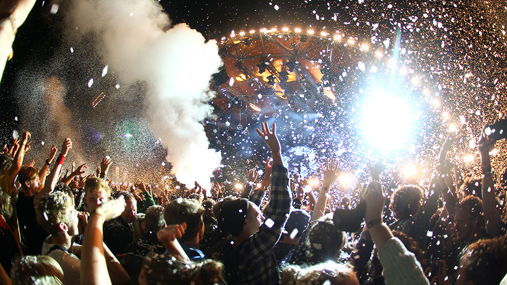 Audience in front of the Orange Stage at Roskilde Festival during confetti, smoke and light show.