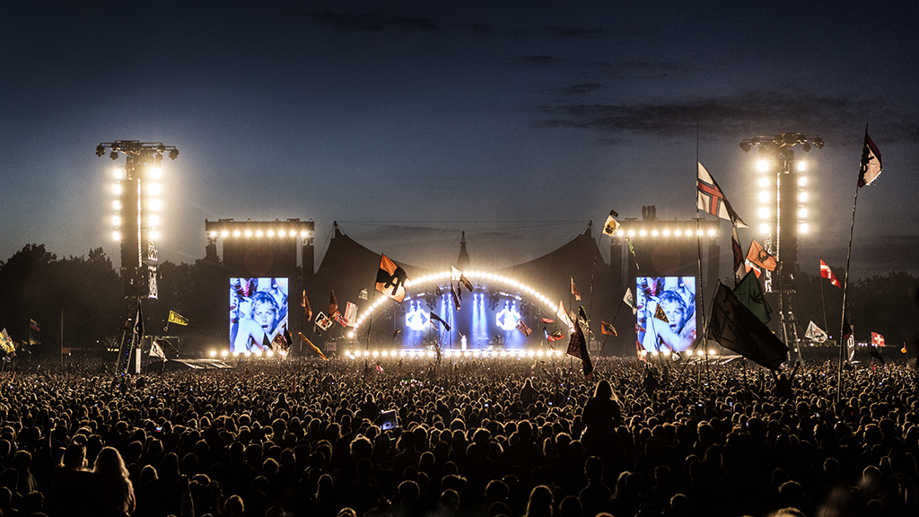 Aftenstemning foran Orange Scene på Roskilde Festival med stor menneskemængde og flag.