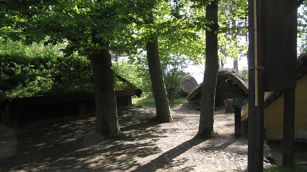 Stråtækte huse mellem træerne på Frederikssund Vikingeboplads.