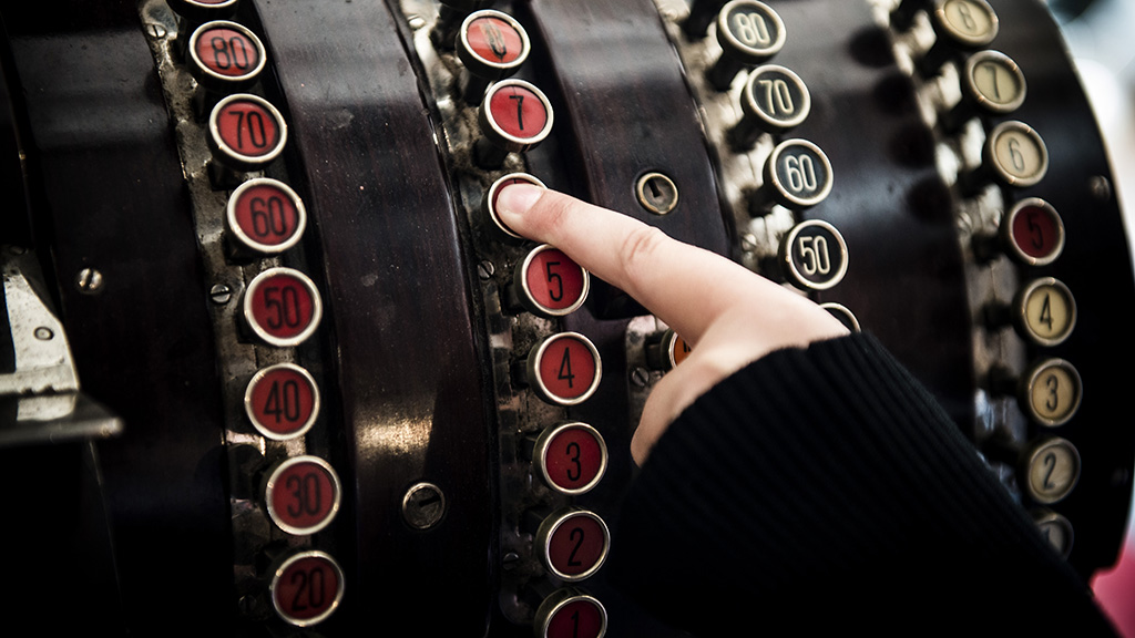 Child pressing a button on an old-fashioned cash register at Lützhøft’s Old Grocer’s Shop.