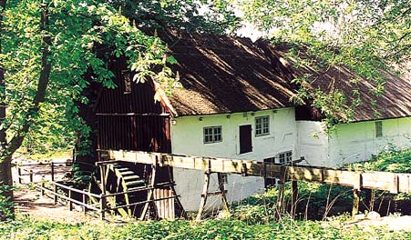 Das weiße Mühlengebäude von Tadre Mølle mit seinem Wasserrad.