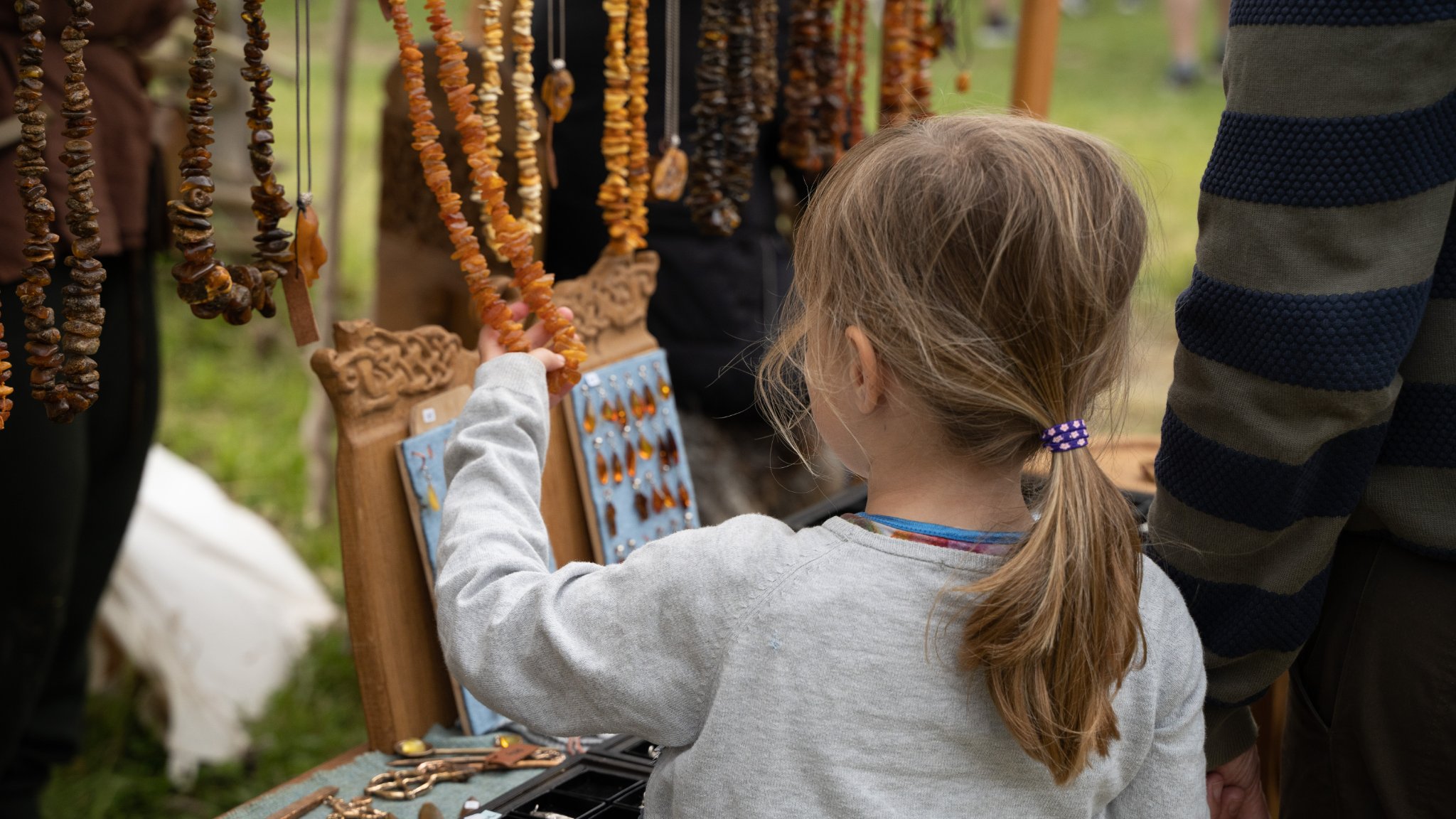 Lille pige kigger på ravsmykker til Vingsted Jernaldermarked