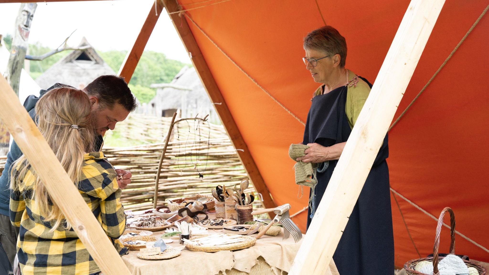 Kvinde står i en orange markedsbod til Vingsted Jernaldermarked