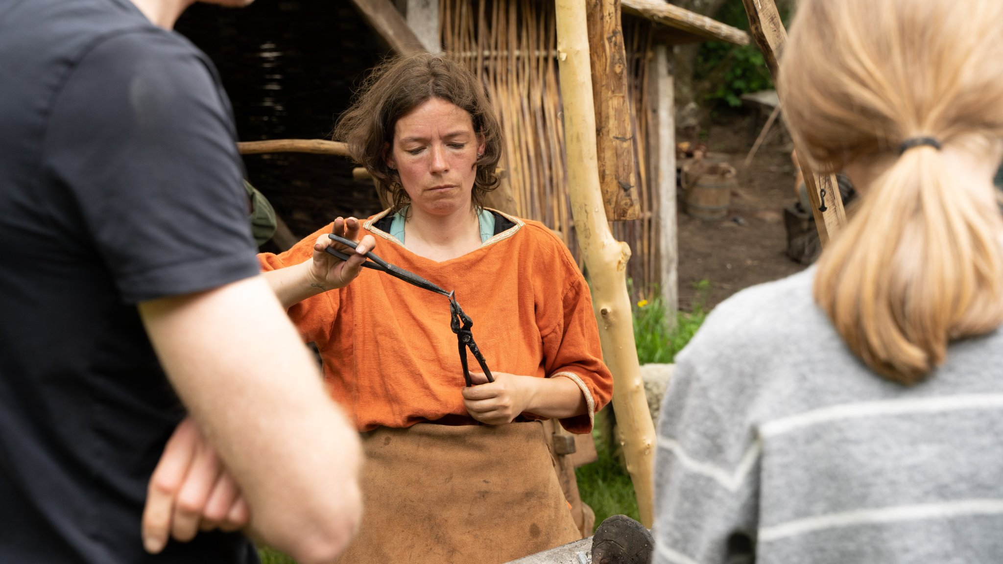 Kvinde i orange smeder til Vingsted Jernaldermarked