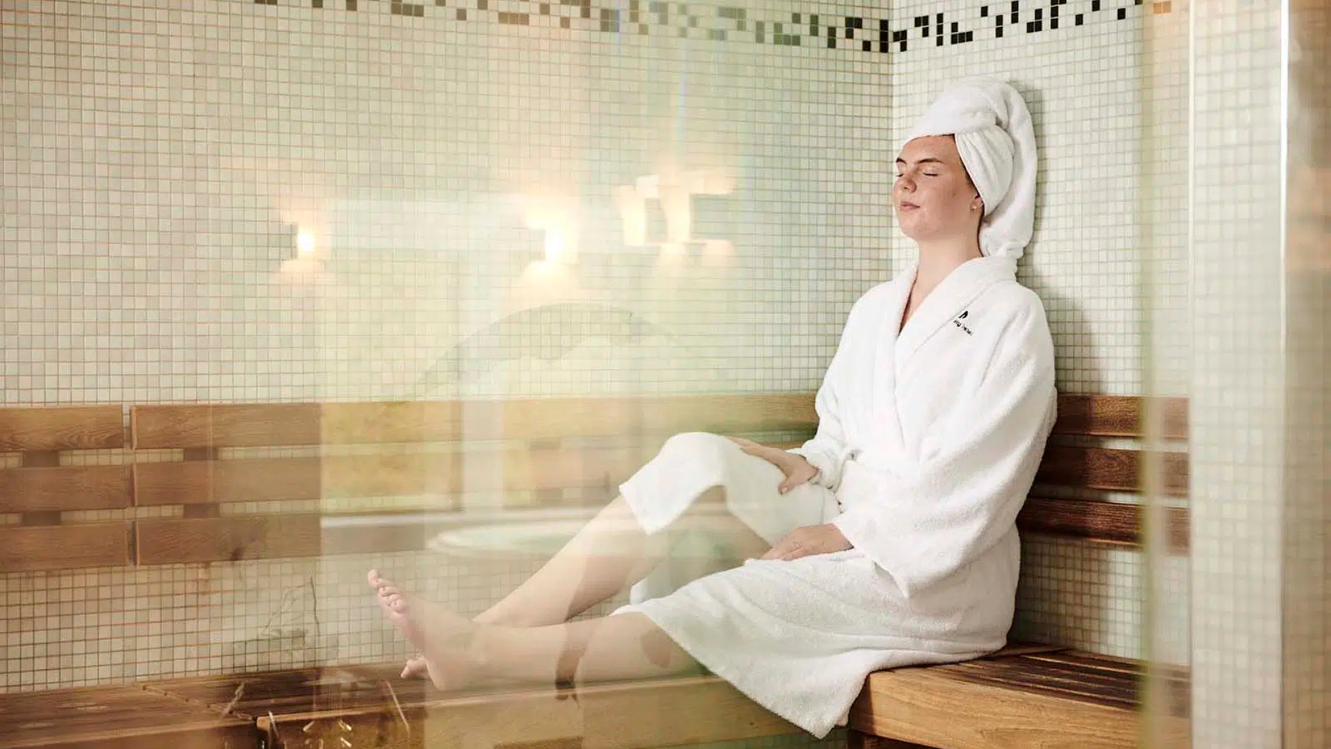 A woman sitting in the sauna at Munkebjerg Hotel’s Fit & Relax after the spa
