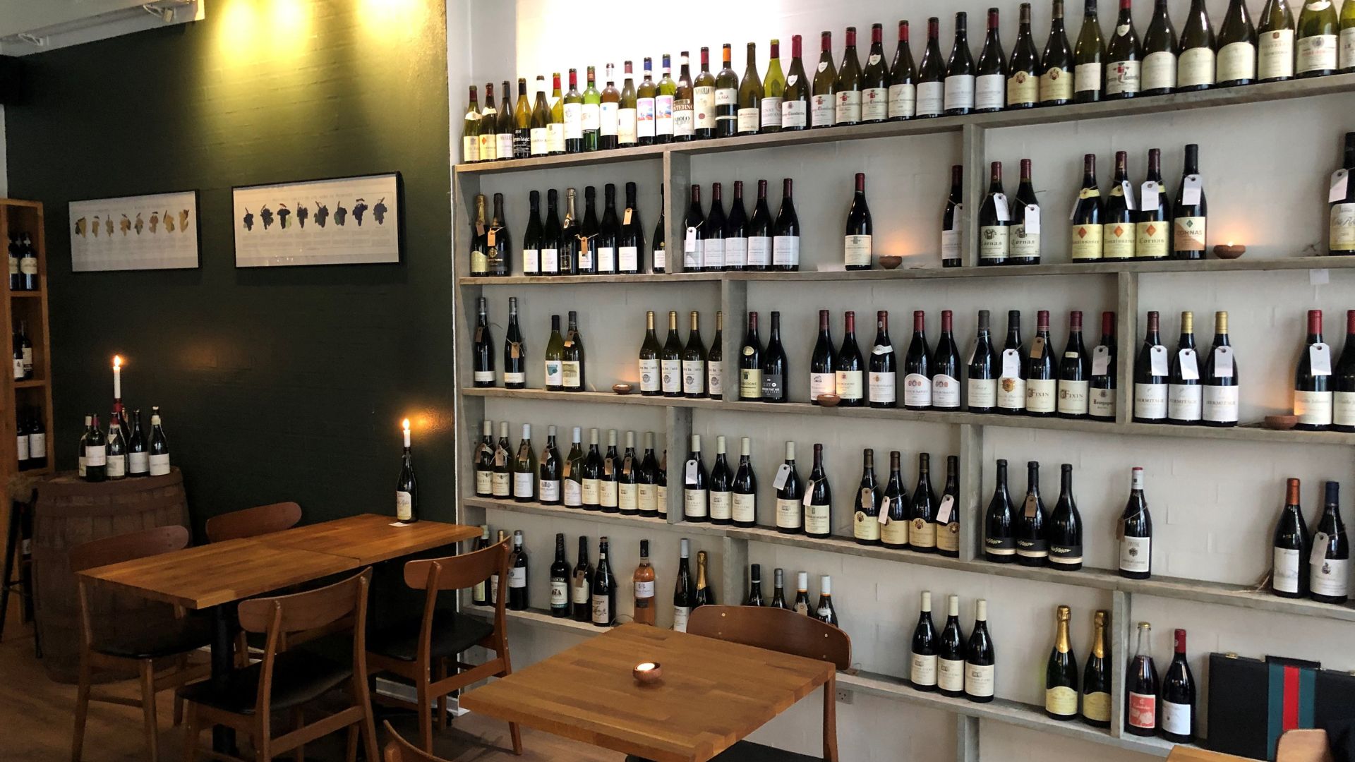 Hyggelig stemning hos Anduma med rækker af vinflasker langs væggen