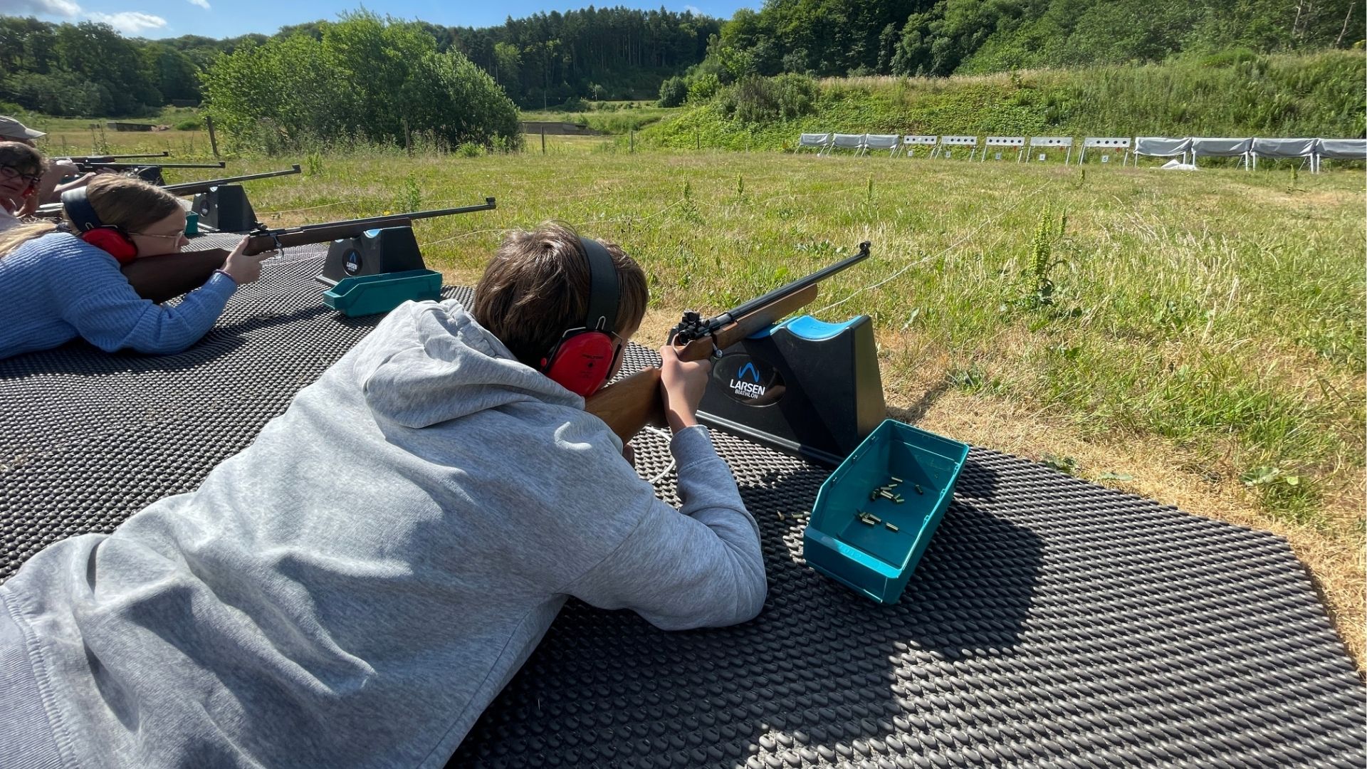 Personen liegen in einer Reihe beim Sportschützentraining in der Natur bei Vingsted Skydebaner