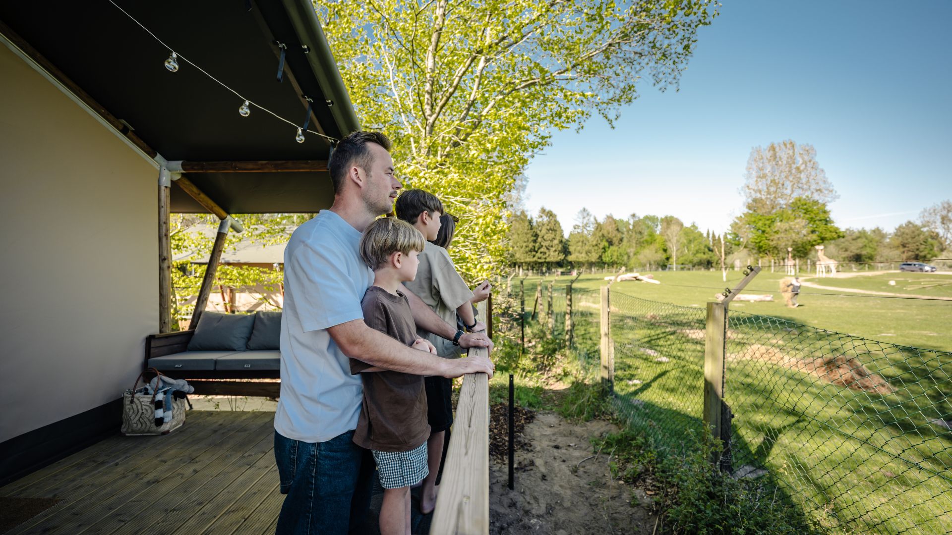 Eine Familie genießt den Blick auf die Savanne von der Terrasse im Safari Camp des Givskud Zoos
