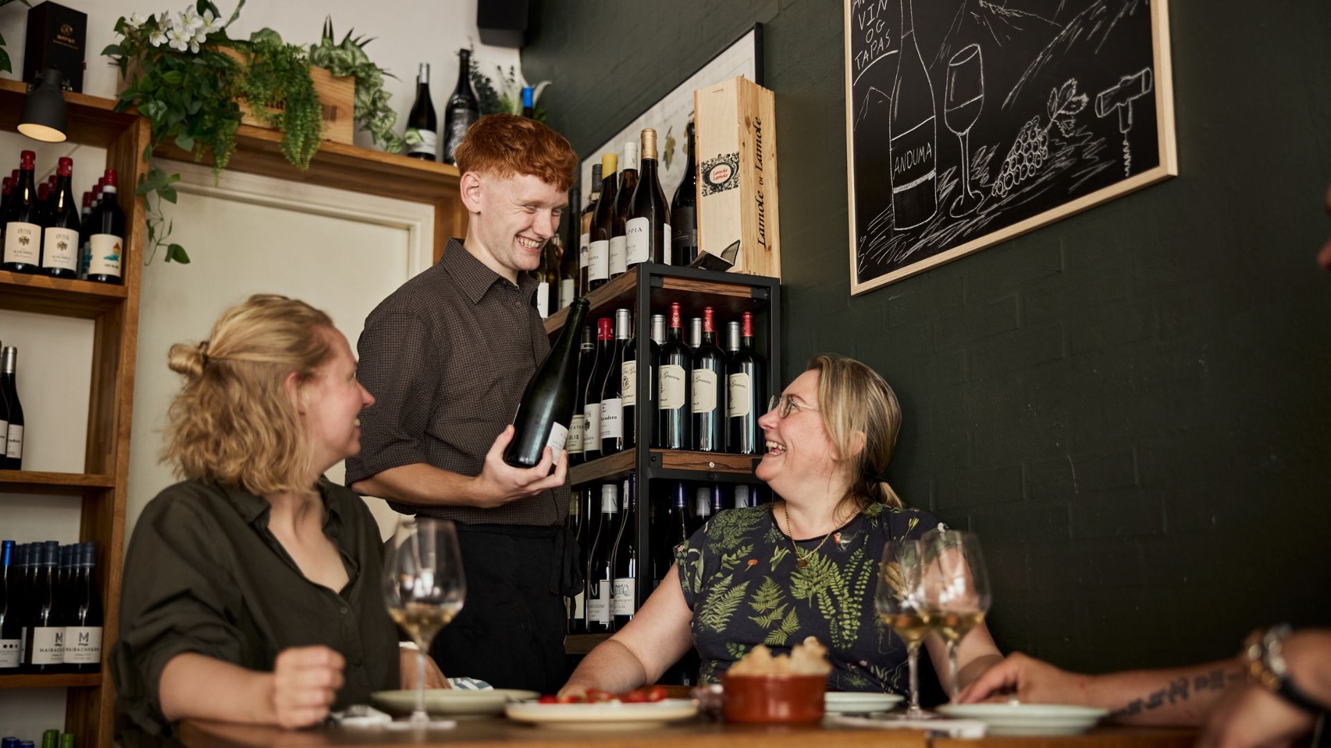 Ein Kellner schenkt gut gelaunten Gästen in der Anduma Weinbar in Vejle Wein ein