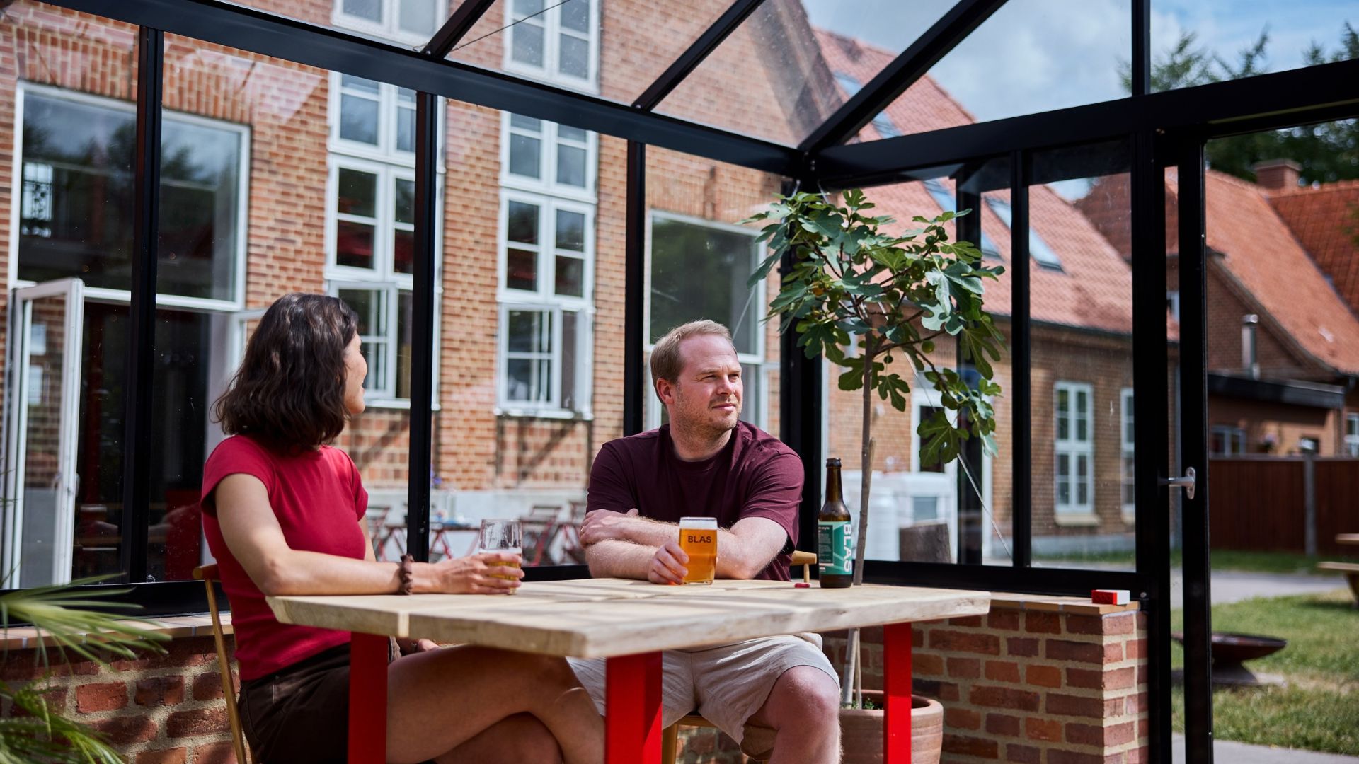 To personer nyder en øl i orangeriet hos BLAS mikrobryggeri