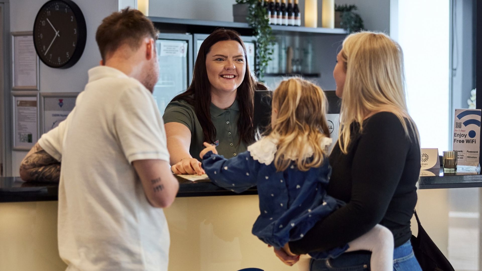 A family gets tips for exploring Vejle from the receptionist at CABINN Vejle
